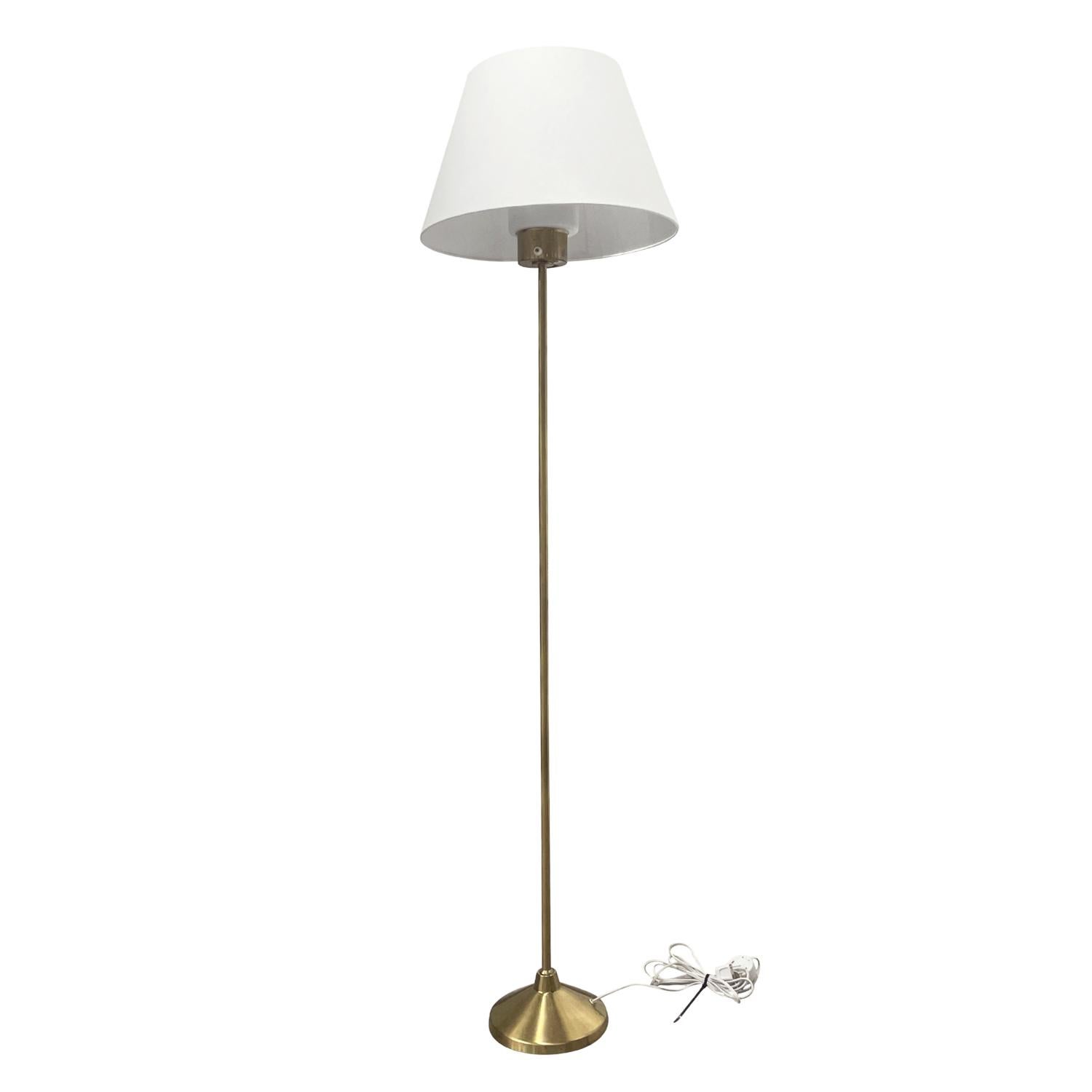 An antique Art Deco Swedish Golvlampa, floor lamp with a new white round shade, made of handcrafted polished brass, designed by Hans-Agne Jakobsson and produced by AB Markaryd in good condition. The Scandinavian reading light is composed with a hand