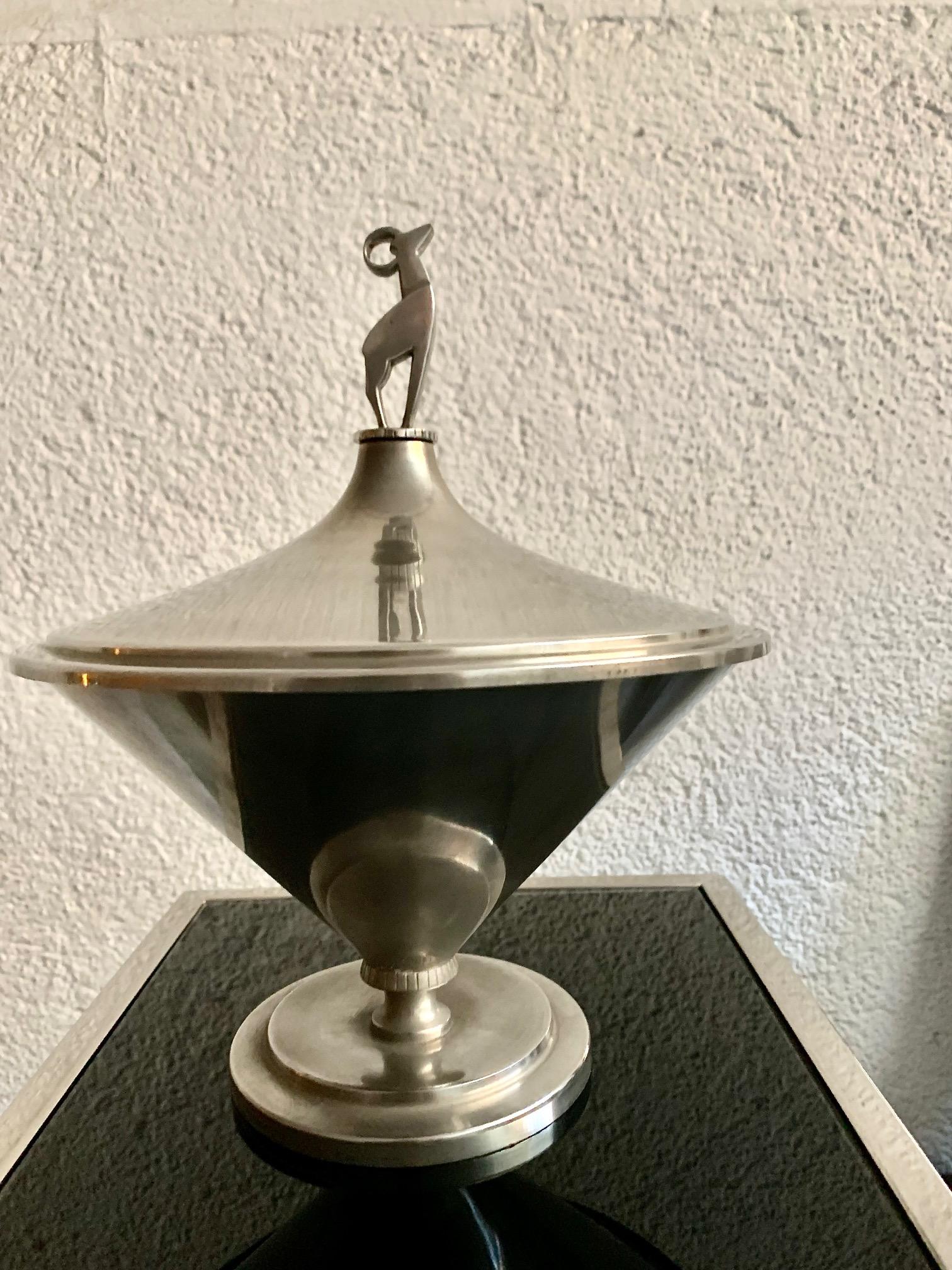 Vase ou urne en étain Art Déco suédois, c'est une pièce spéciale avec une base dont le vase part d'une forme conique, il a un couvercle surmonté d'une figure représentant un animal ressemblant à un cerf, Signé en bas par Tyringe Konsthanverk.