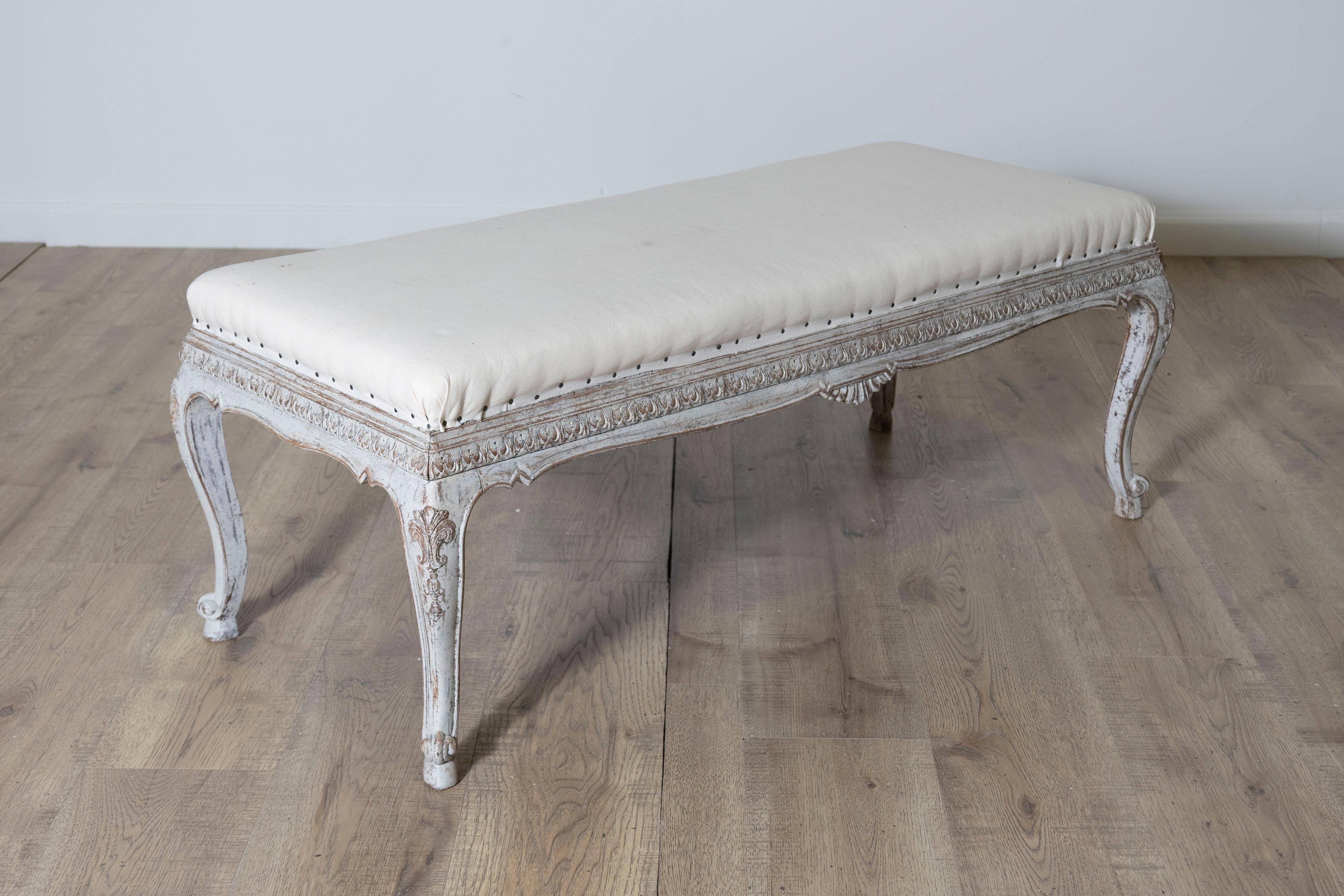 Este elegante banco sueco del siglo XX muestra la refinada artesanía y la sencillez atemporal características del diseño escandinavo. Fabricado en pino tallado, el banco presenta un acabado pintado en blanco envejecido que resalta sus intrincados