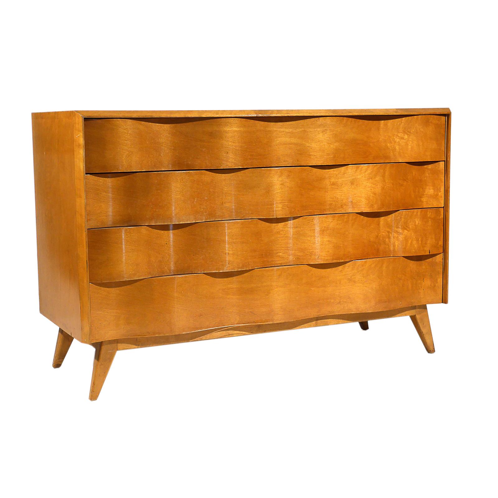 A vintage Mid-Century Modern Swedish commode with four large drawers, made of hand carved Burlwood and Birchwood, designed by Edmond J. Spence and produced in Sweden, in good condition. The Scandinavian wave front chest of drawers is supported by