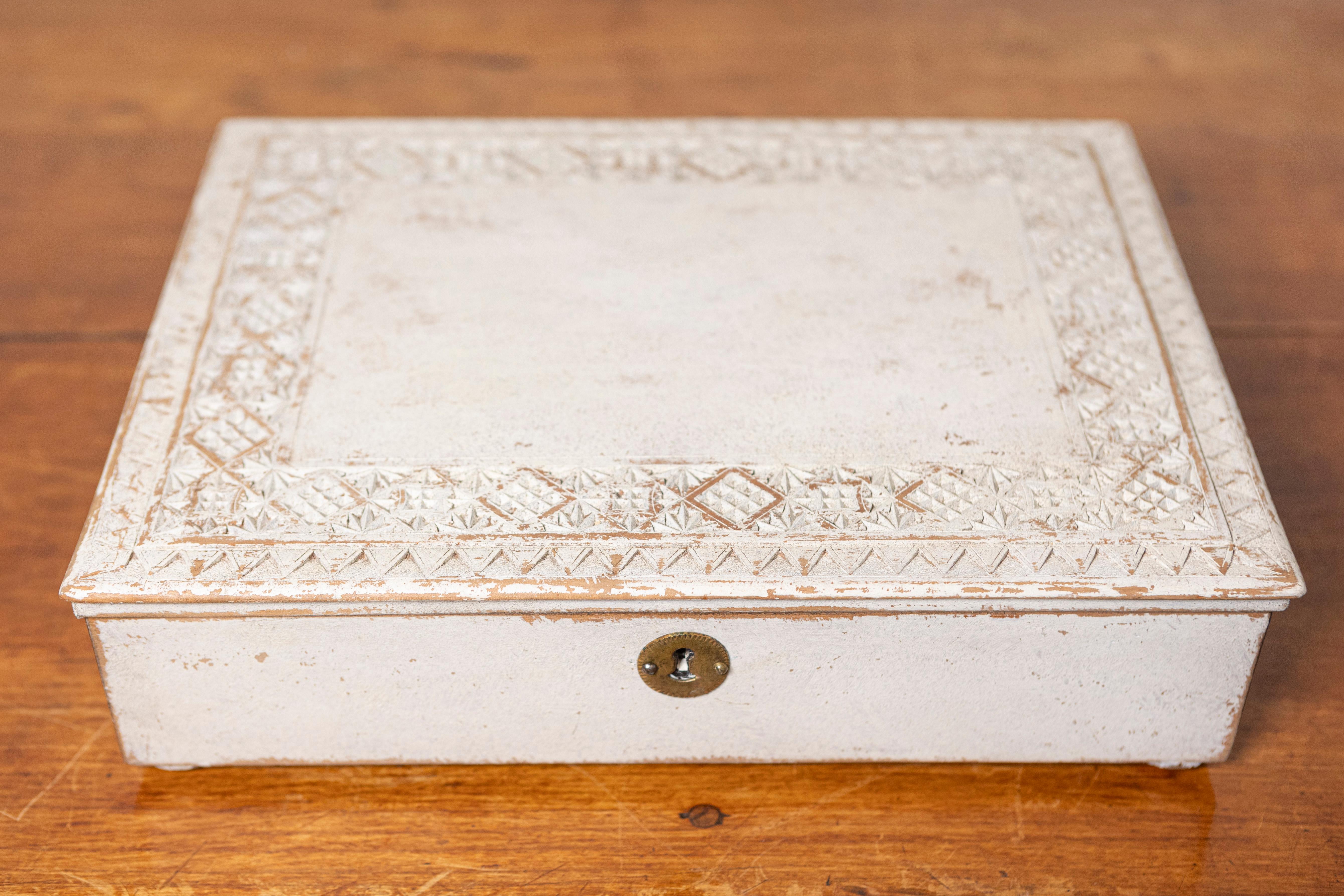 This 20th-century Swedish box is a charming piece of craftsmanship, blending functionality with rustic elegance. The exterior is decorated with a textured, hand-carved geometric pattern that frames the lid, adding depth and visual interest. Its