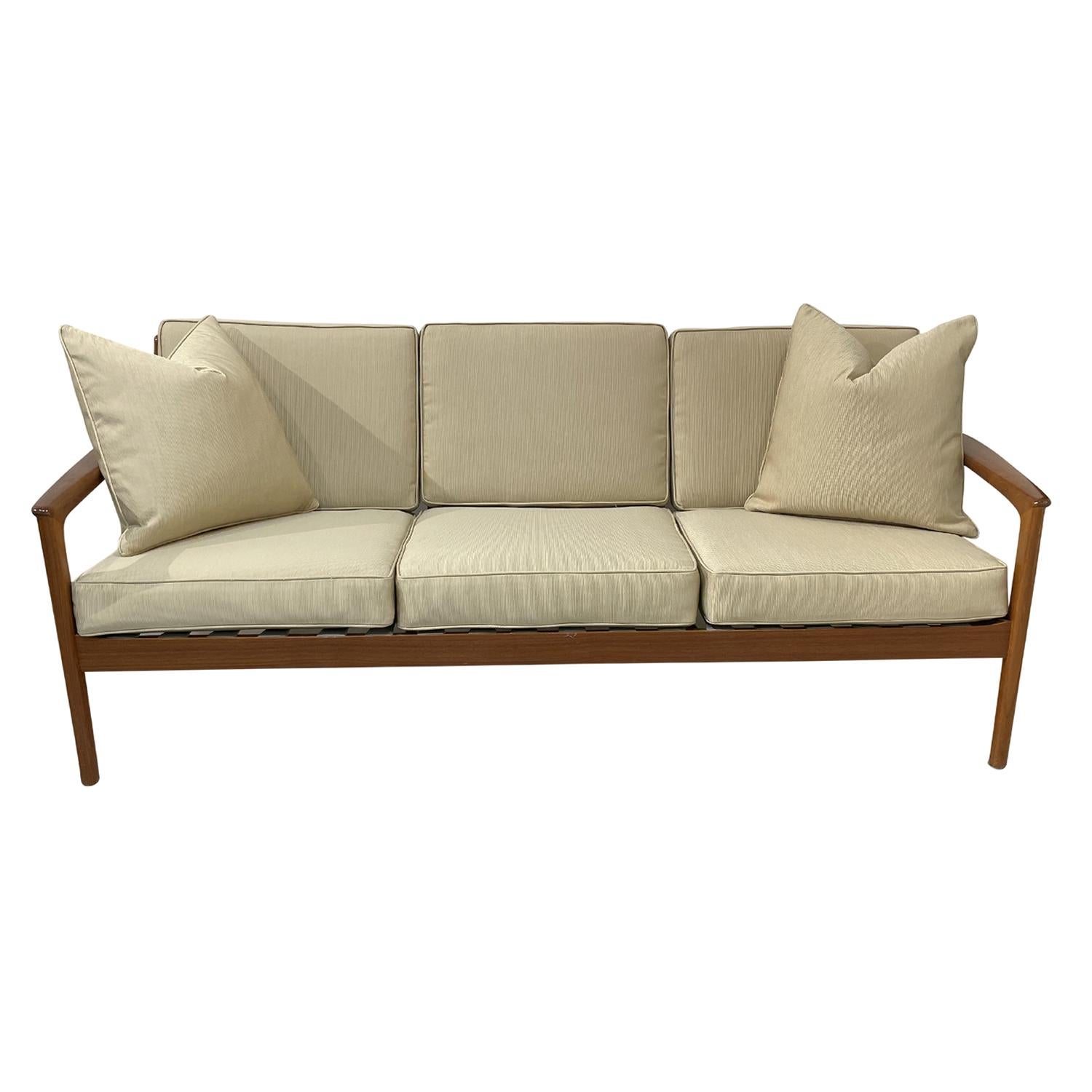 A dark-brown, vintage Mid-Century Modern Swedish three seater sofa with two pillows made of hand crafted polished Teakwood, designed by Folke Ohlsson and produced by DUX, in good condition. The Scandinavian settee, canapé has a slightly inclined