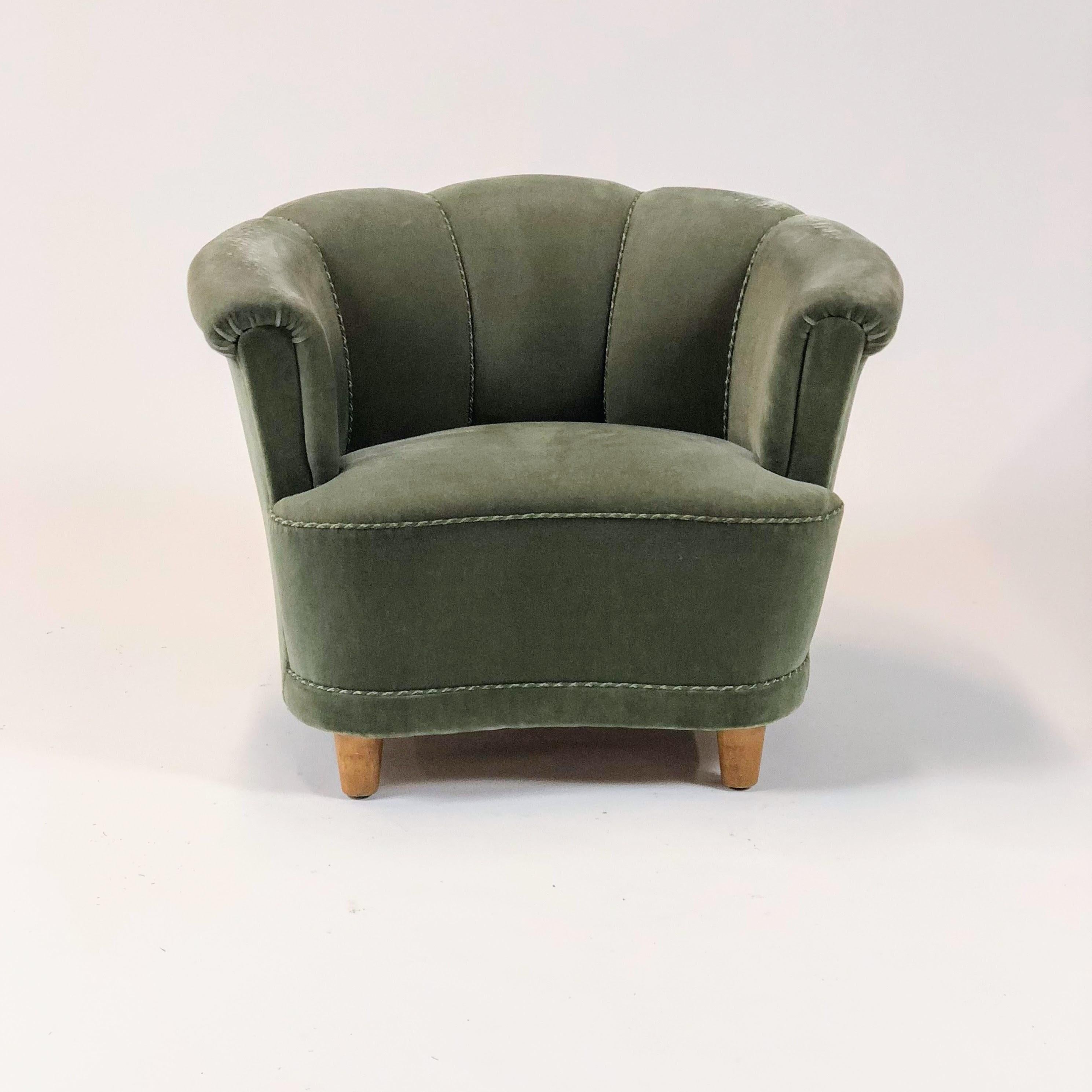 A pair of mid-century Swedish lounge chairs. Upholstered in an interesting green gray velour with scalloped back, piping detail on outer edges, and beech feet.