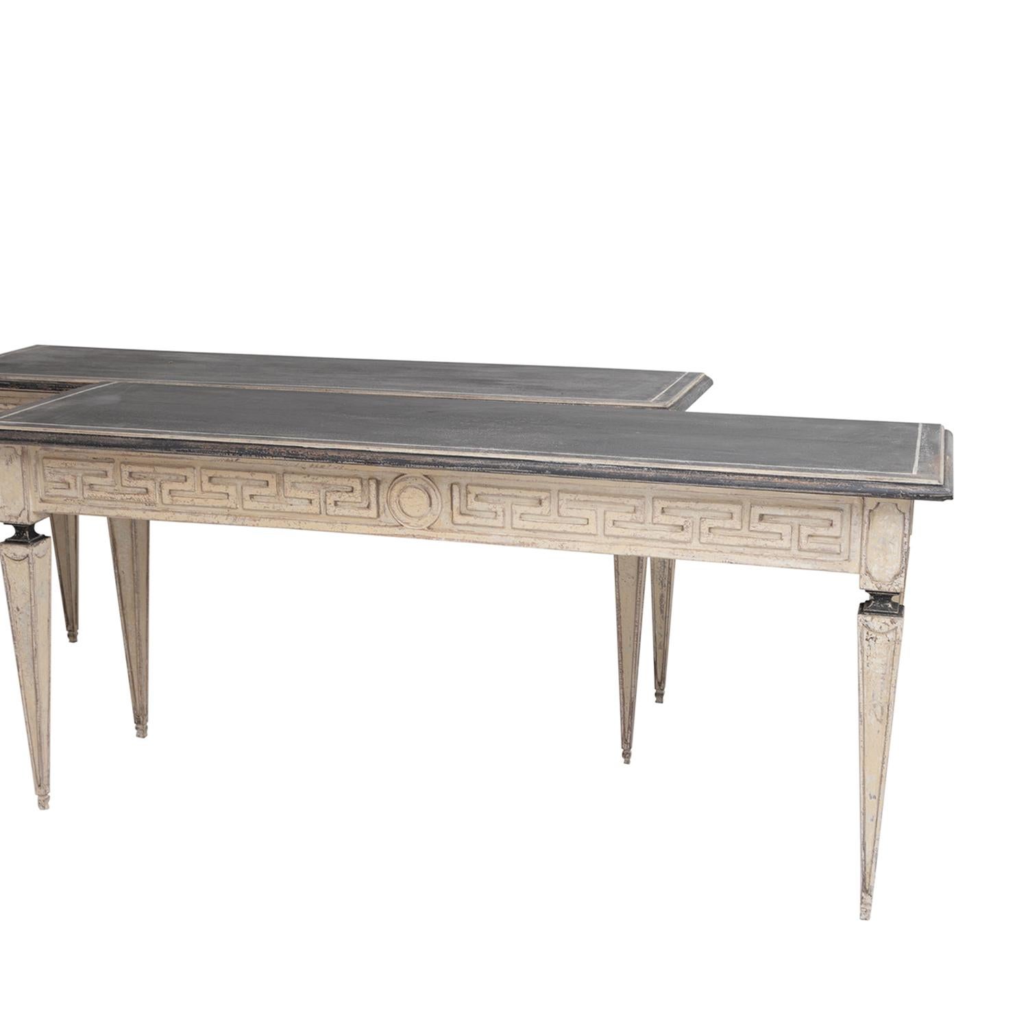 An early 20th Century, antique pair of Swedish Gustavian freestanding console tables made of hand crafted painted Walnut, in good condition. The detailed Scandinavian end tables are composed with a dark-grey top, particularized by wood carvings,