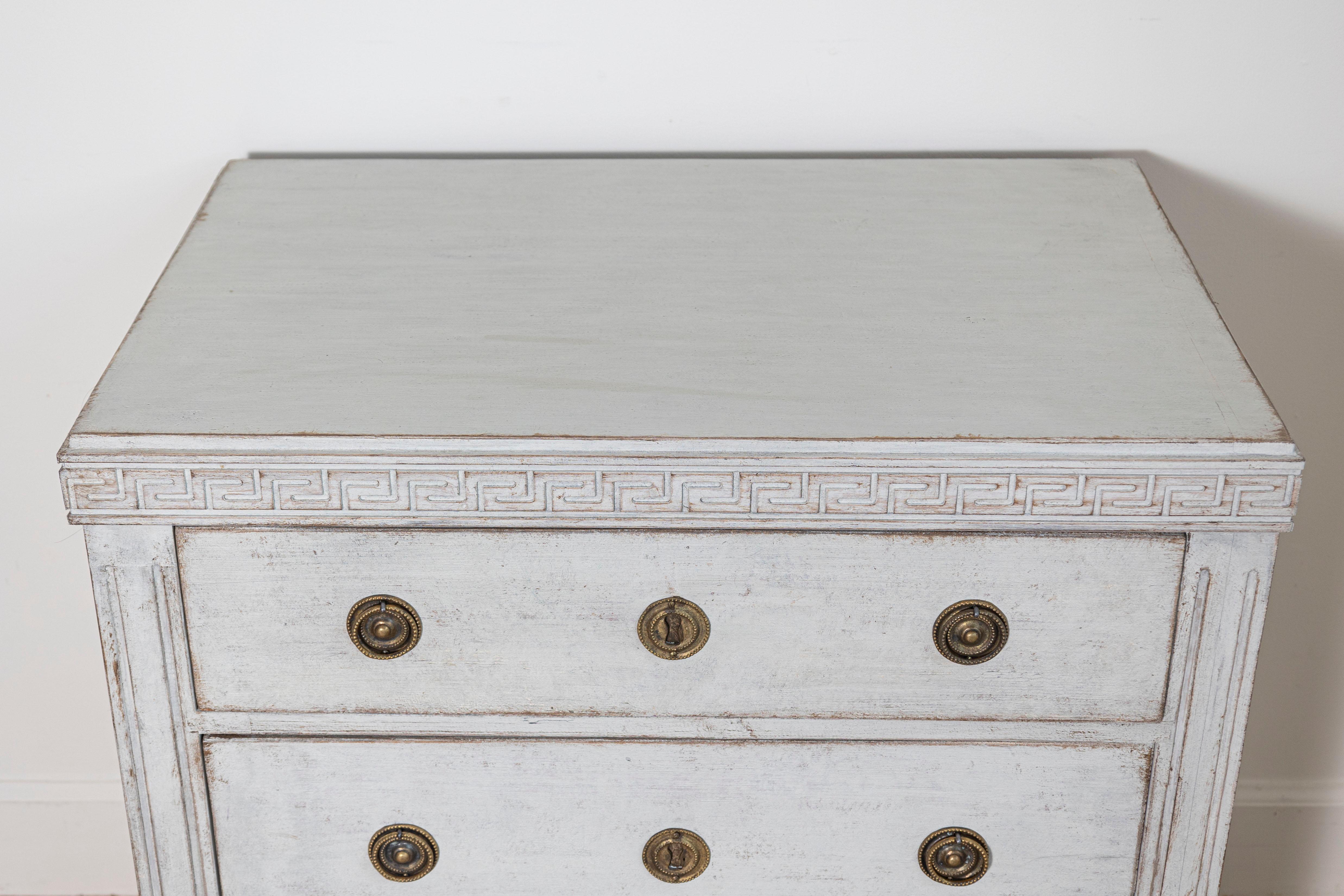 Eine raffinierte Kommode im schwedischen Gustavianischen Stil des 20. Jahrhunderts, die die zeitlose Eleganz und Handwerkskunst dieses ikonischen Designs unterstreicht. Das Stück ist in einem sanften, gedämpften Grau lackiert, das durch eine schöne