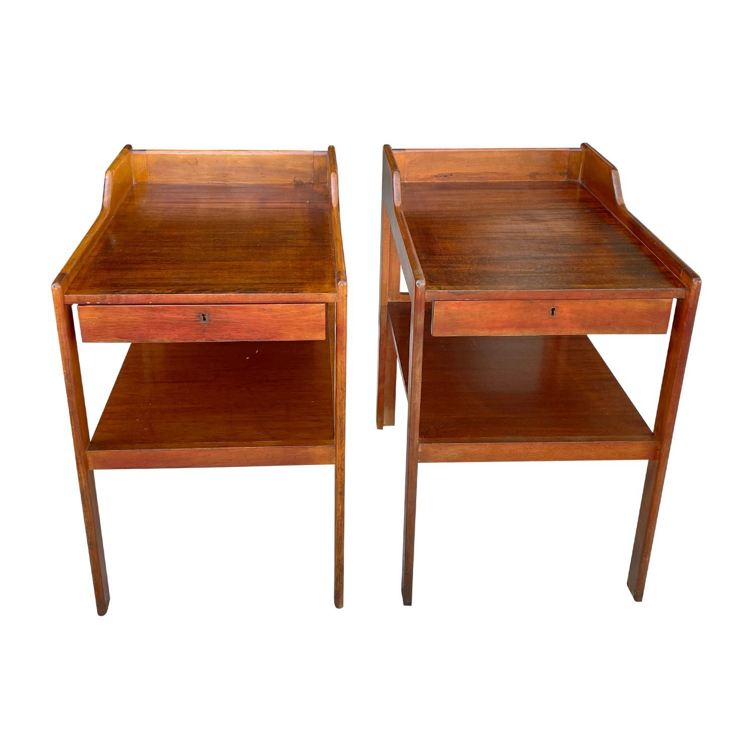 A light-brown, vintage Mid-Century Modern Swedish pair of bedside tables made of hand carved Mahogany, each of them is composed with one drawer, shelf and a brass handle, consisting its original brass hardware and key, standing on four straight