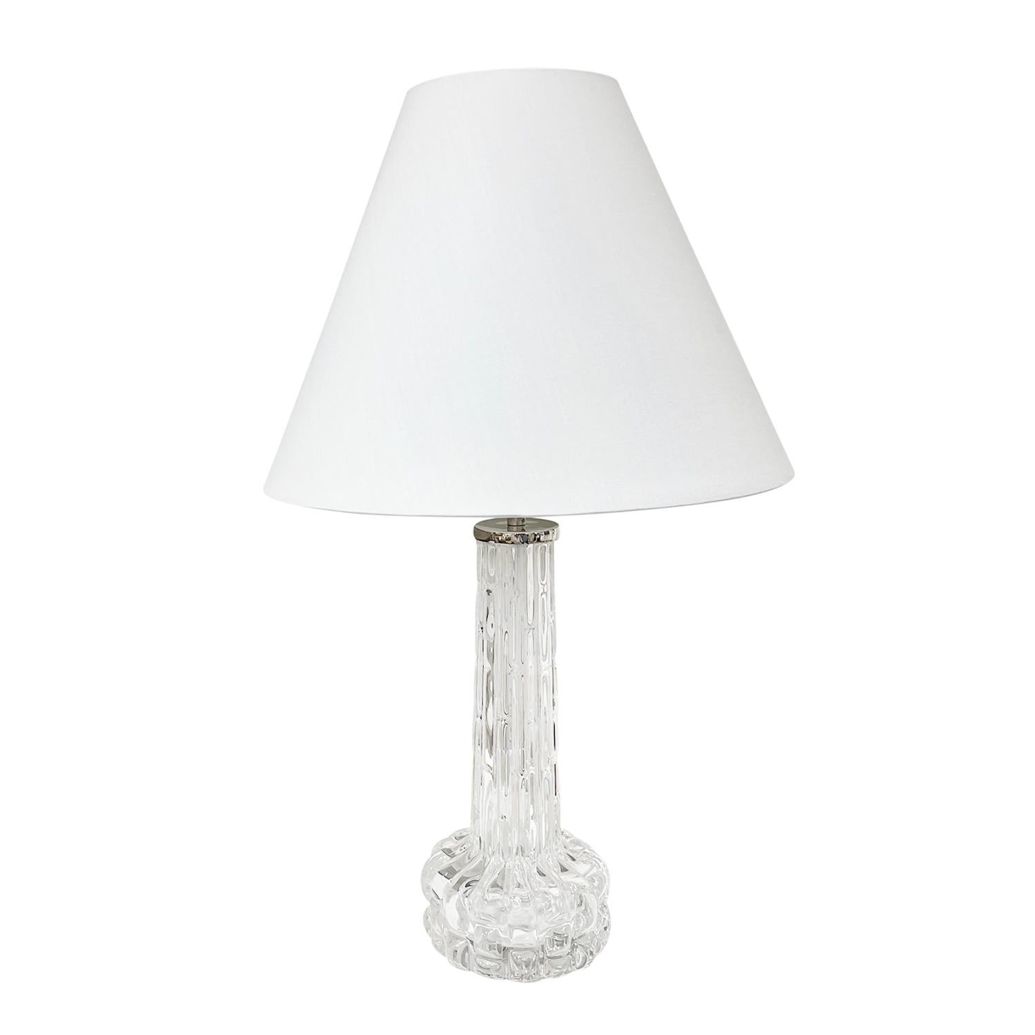 A vintage Mid-Century Modern Swedish desk lamp with a new white round shade, made of hand blown clear Orrefors glass, designed by Carl Fagerlund and produced, signed by Orrefors in good condition. The Scandinavian table light is enhanced with a