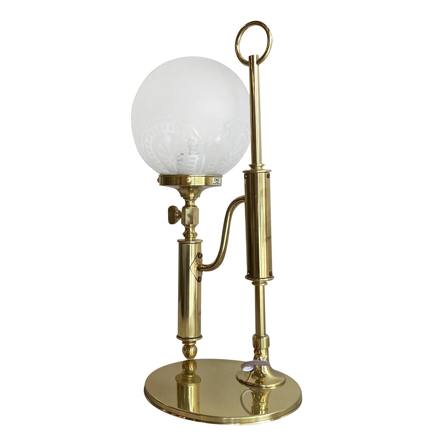A vintage Mid-Century Modern Swedish table lamp made of hand crafted polished brass, designed by Helmer Andersson and produce by Örsjö in good condition. The detailed Scandinavian light is composed with a round, open hand blown polished glass shade,