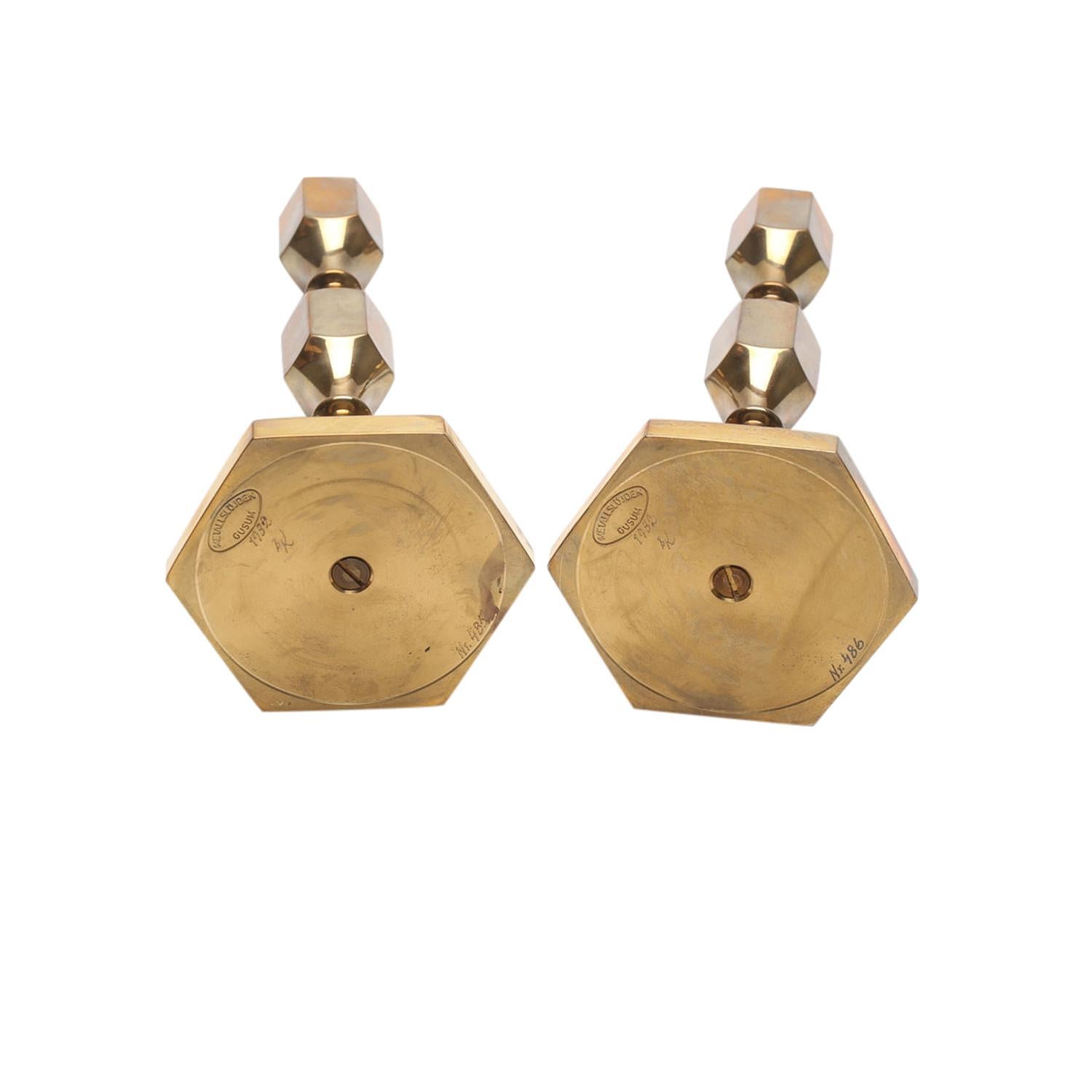 A gold, vintage Mid-Century modern Swedish pair of candle holders made of hand crafted polished brass, designed by Lars Bergsten and produced by Metallslojden Gusum in good condition. The arched Scandinavian sticks are signed. Manufacturer label at