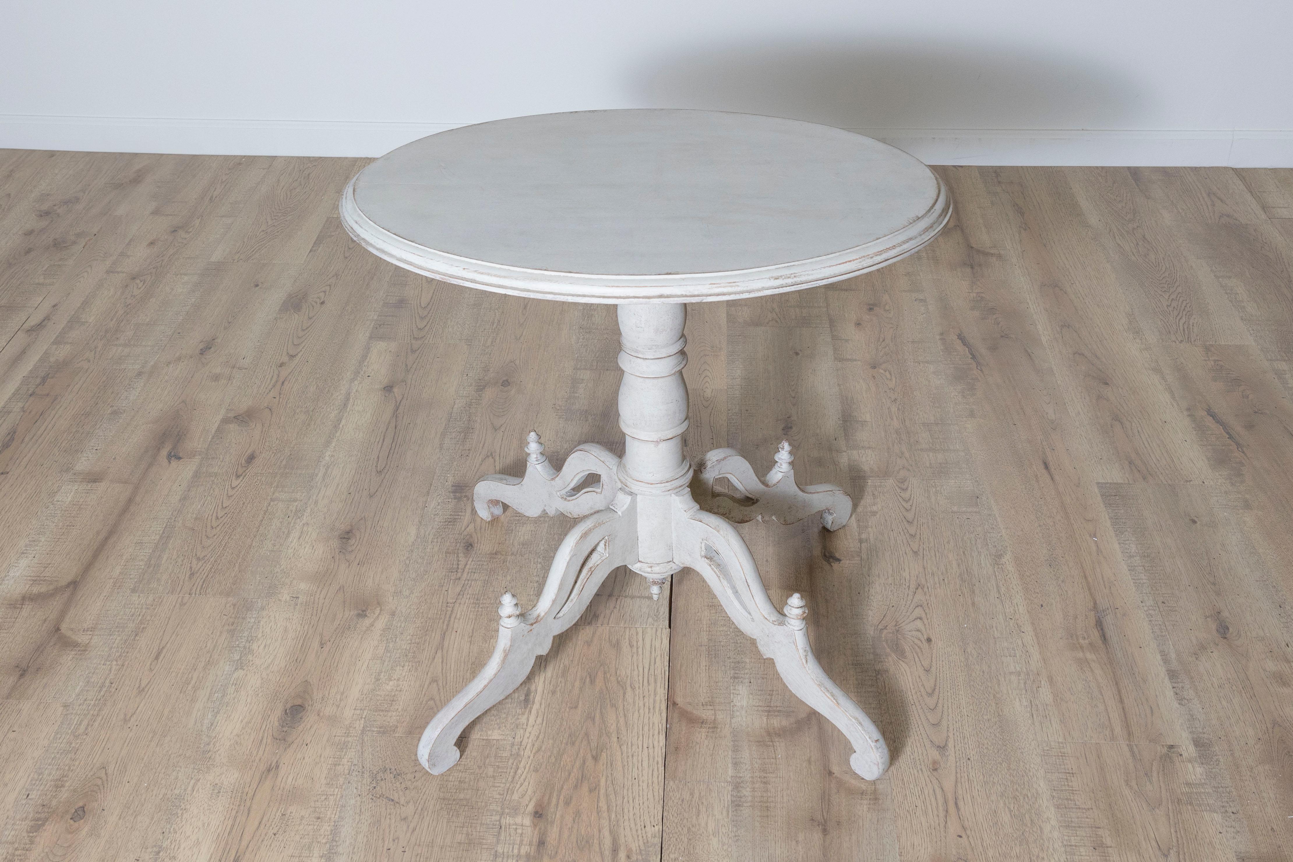 Cet élégant guéridon suédois du XXe siècle incarne la simplicité intemporelle et le savoir-faire artisanal du design scandinave. La table présente une base en pin magnifiquement sculptée avec une finition peinte en blanc vieilli, ajoutant une touche