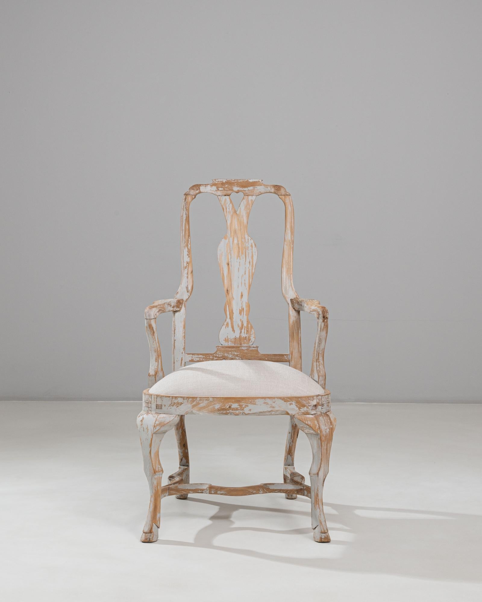 Cette chaise de salle à manger en bois patiné de style néo-rococo suédois du XXe siècle présente une silhouette élégante et sculpturale inspirée du design suédois du XVIIIe siècle. Le cadre présente un haut splat percé aux courbes douces et aux