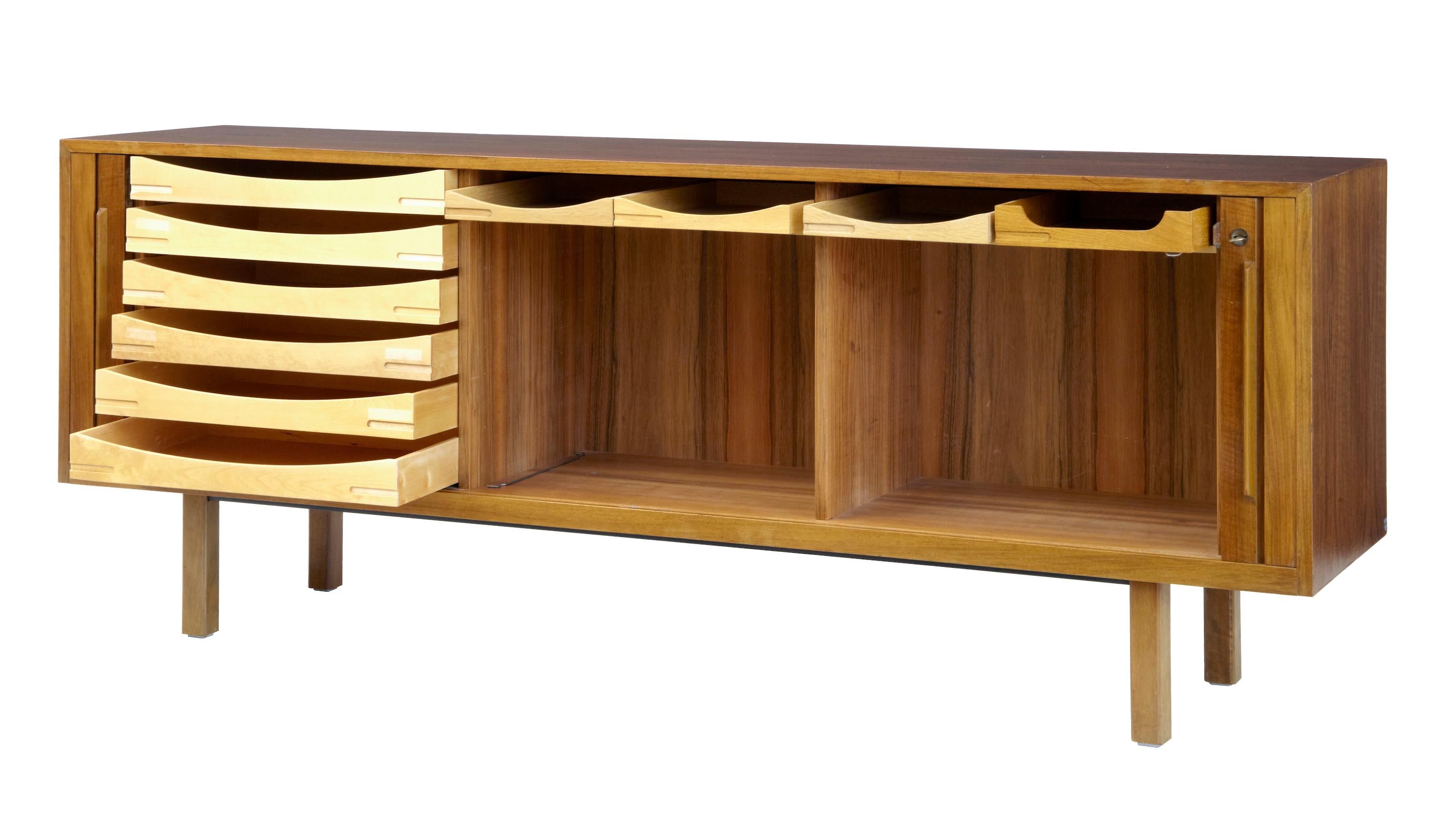Good quality sideboard by Swedish makers Atvidabergs, circa 1965.
Tambour fronted which opens to reveal a semi fitted interior.
Three compartments, left hand side with a bank of six drawers, the other two sections with two drawers in the top (1