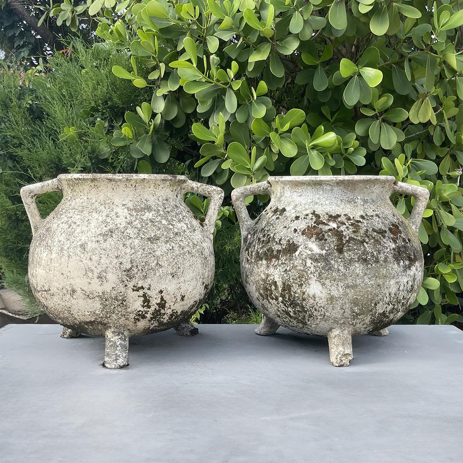 A pair of vintage Willy Guhl Cauldron-shaped planters elevated of short three legs and two lateral handles, in good condition. Each of the Swiss Eternit garden planters are created in a light weight cement, each having its heavy original weathered