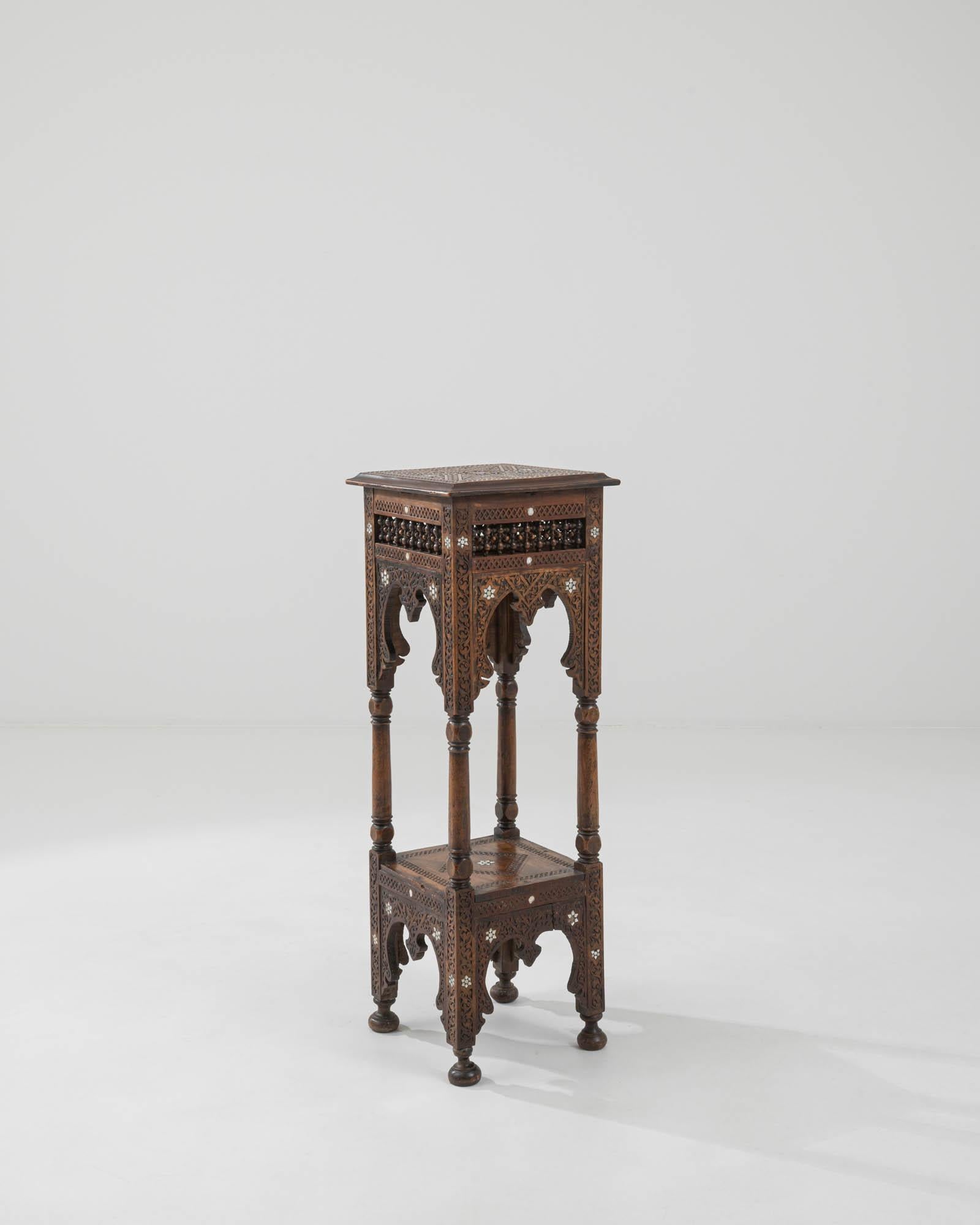 A wooden pedestal created in 20th century Syria. Characteristic of Arabic design, this lovely pedestal is painstakingly carved from head to toe in elaborately described geometric patterning, which make the entirety of the piece shimmer with unique
