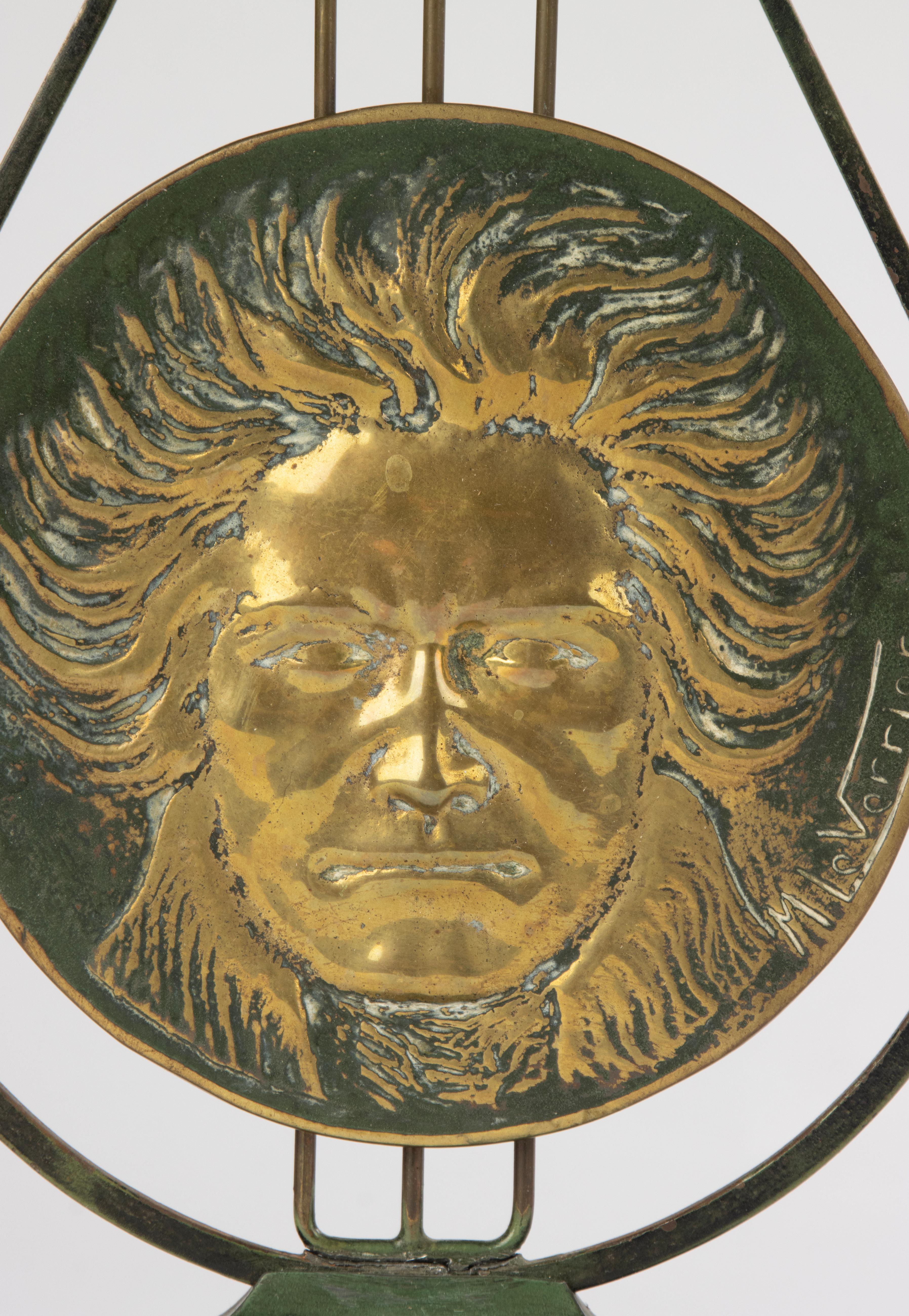 Striking Art Deco table sculpture by renowned French artist Max Le Verrier, featuring a dramatic brass portrait medallion of Ludwig van Beethoven, set within a stylized lyre-shaped frame. The piece is mounted on a green-patinated spelter base and