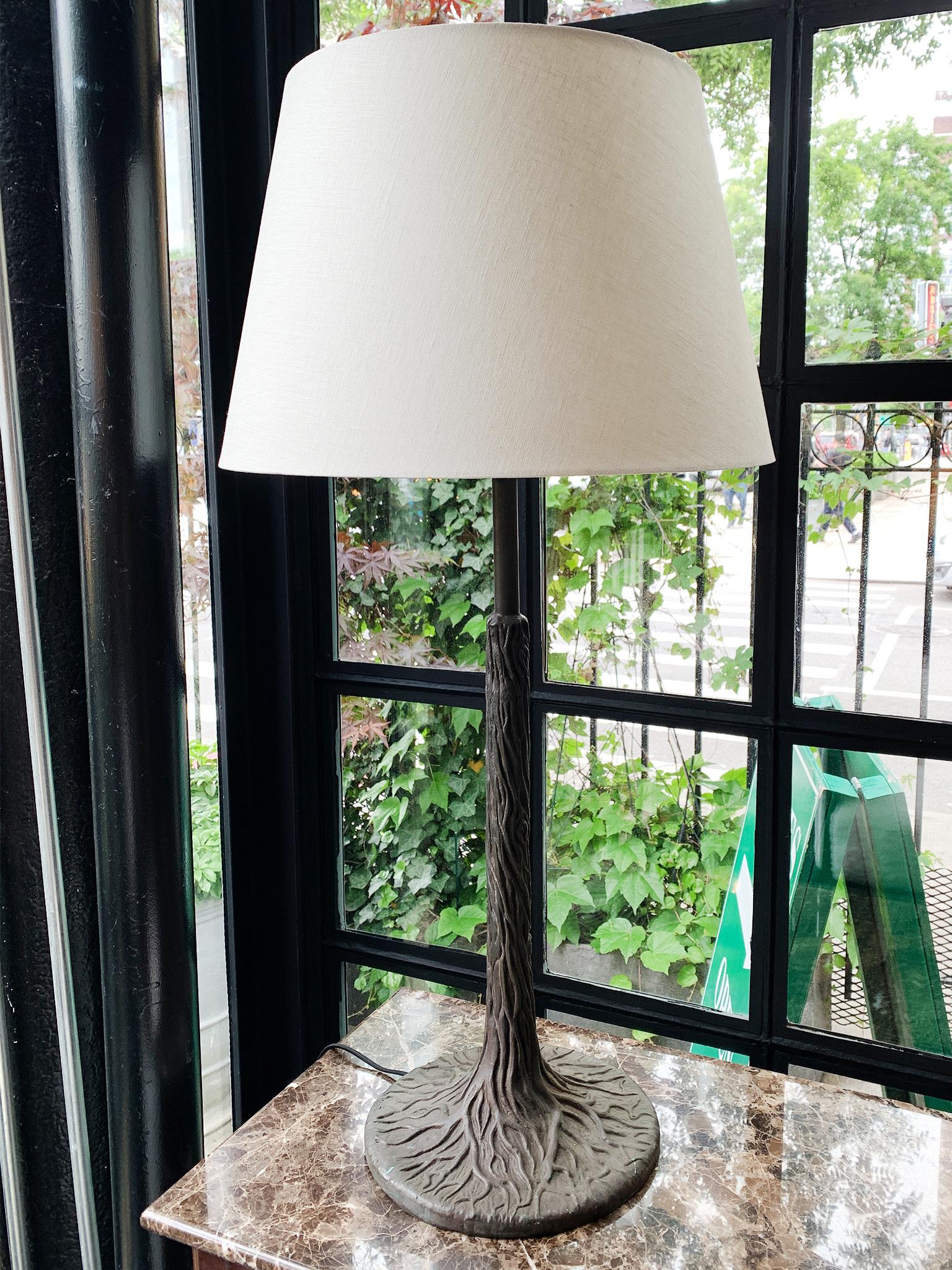 This beautifully sculptural cast-iron table lamp mimics the organic forms of a tree, from the gnarled roots at its base to the bark-like textures of its body. The lamp has been newly rewired and has a single bulb socket. It has a new brass harp and