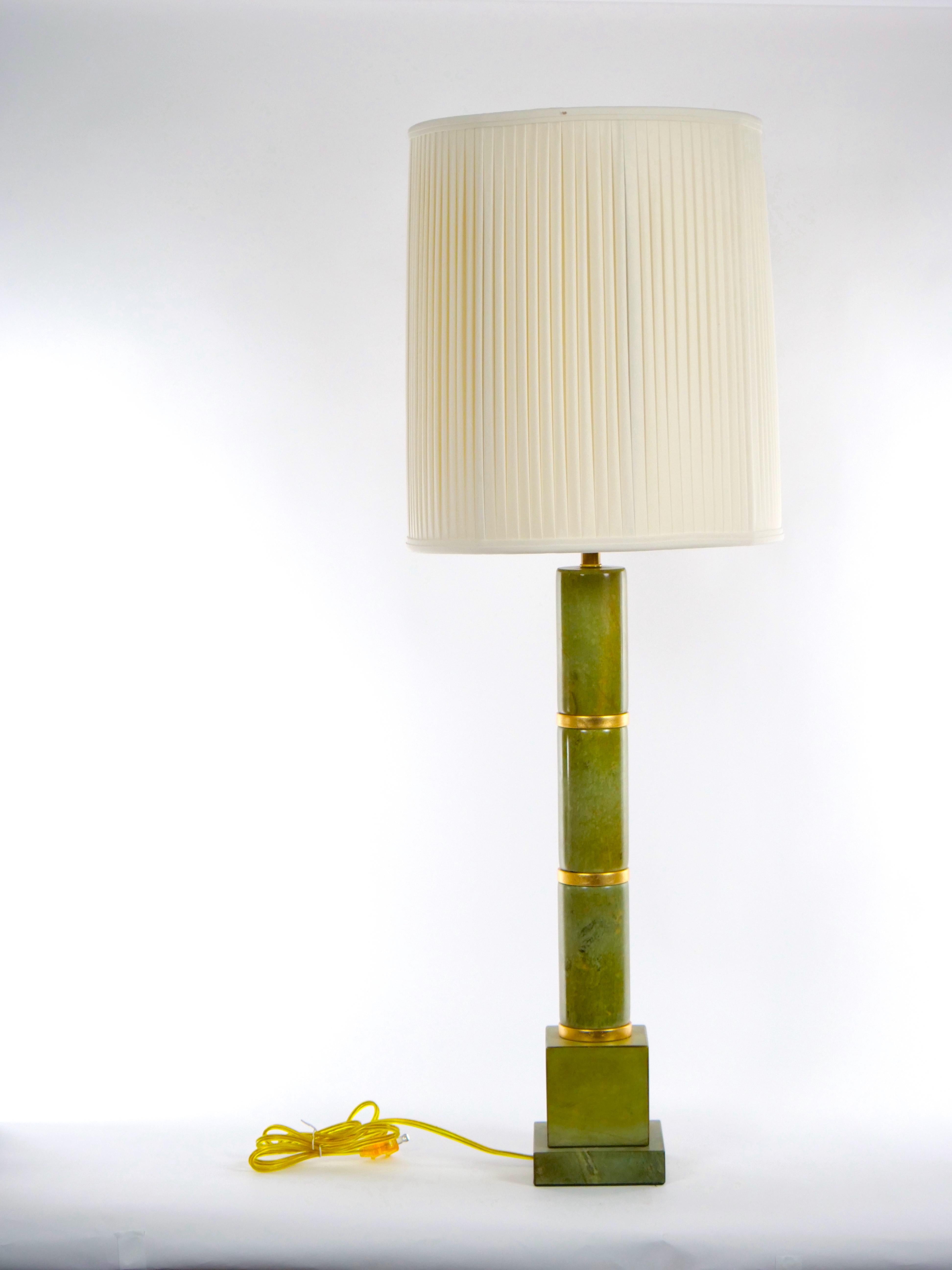 Paire de lampes de table de style art déco en jade vert et or doré. Chaque lampe présente un stock de trois pièces rondes de jade vert en forme de poteau avec une décoration dorée entre les deux, reposant sur une base de forme carrée. Chaque lampe