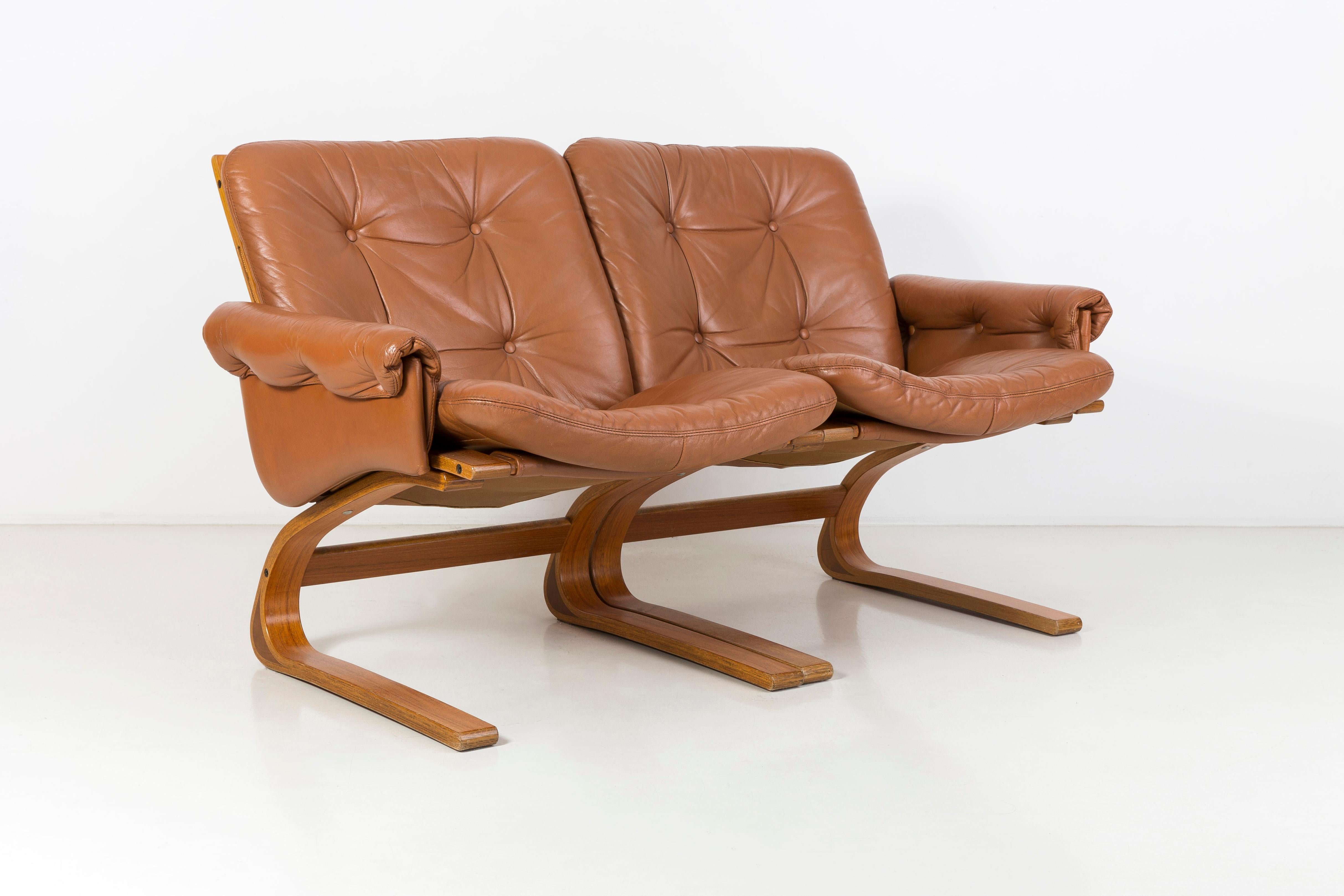 Norwegian Kengu sofa made by the Rybo Rykken manufacture, whose designers are Elsa & Nordahl Solheim. It was produced in 1976. The frame of the sofa is made of bent teak wood. The upholstery is original, made of genuine leather. This sofa is an icon