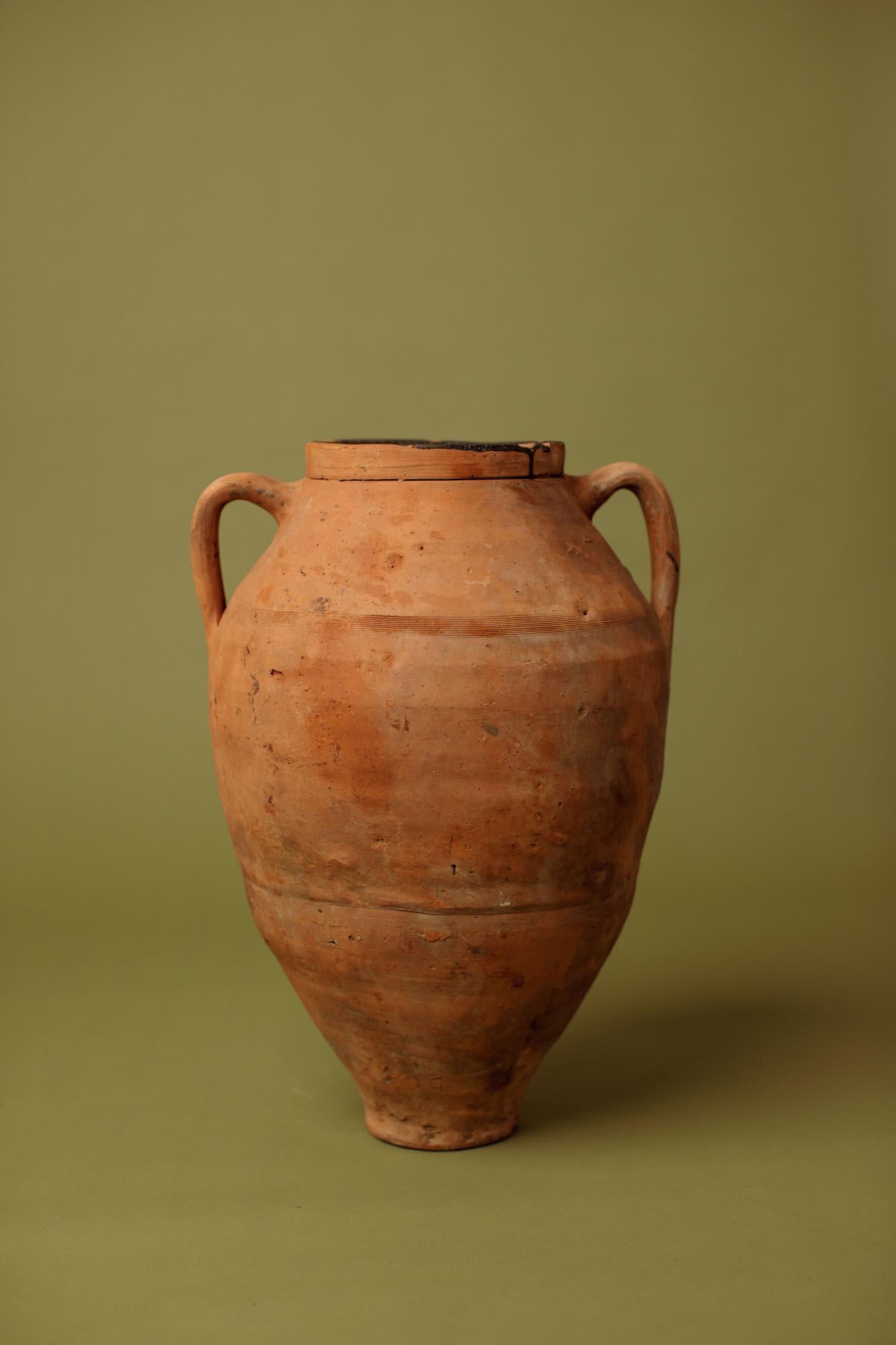 Questa giara in terracotta del XX secolo proviene dall'Anatolia occidentale ed è stata realizzata per la conservazione e il trasporto di Oliver e dell'olio in ambienti rurali. La forma alta e affusolata - con spalle larghe e stabili - riflette la