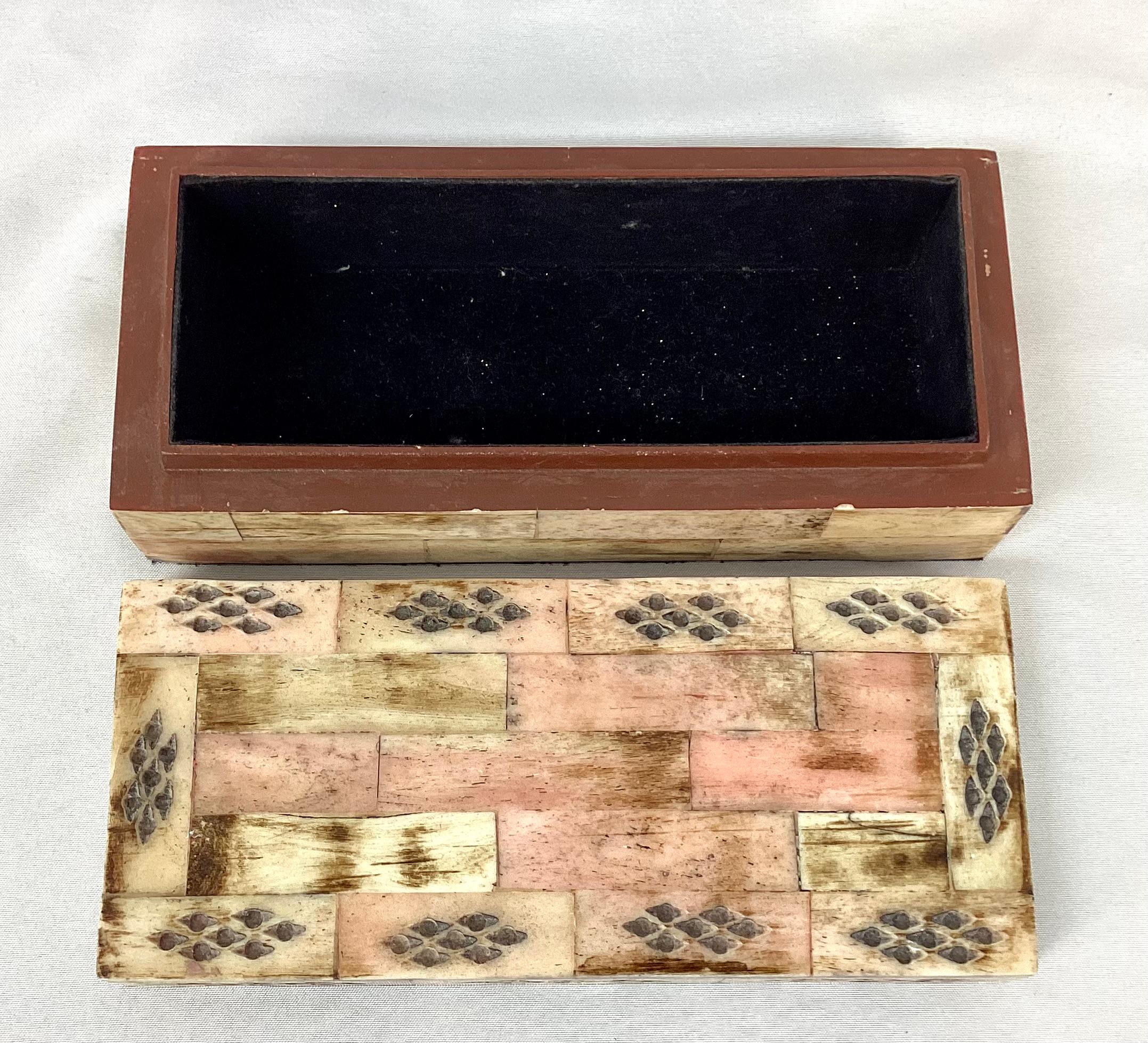 An elegant modern style tessellated bone trinket box with black felt-lined interior. Mostly cream in color, but does have hints of light pink throughout. Small harlequin shaped cut outs along top add flair.