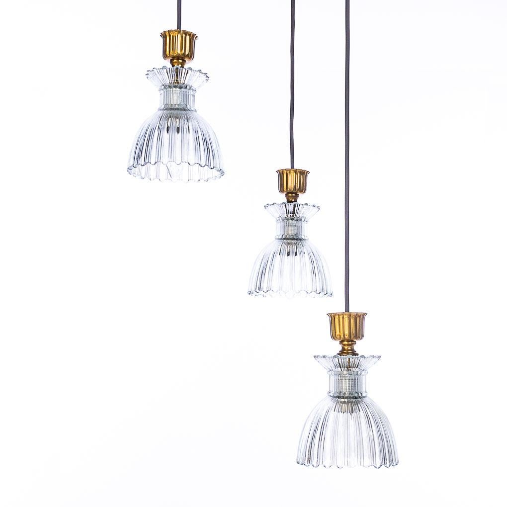 Stylish chandelier consists of 3 arms with beautiful pressed glass cups. The combination of the brass, glass and random length of the stems, make it an eye catcher!