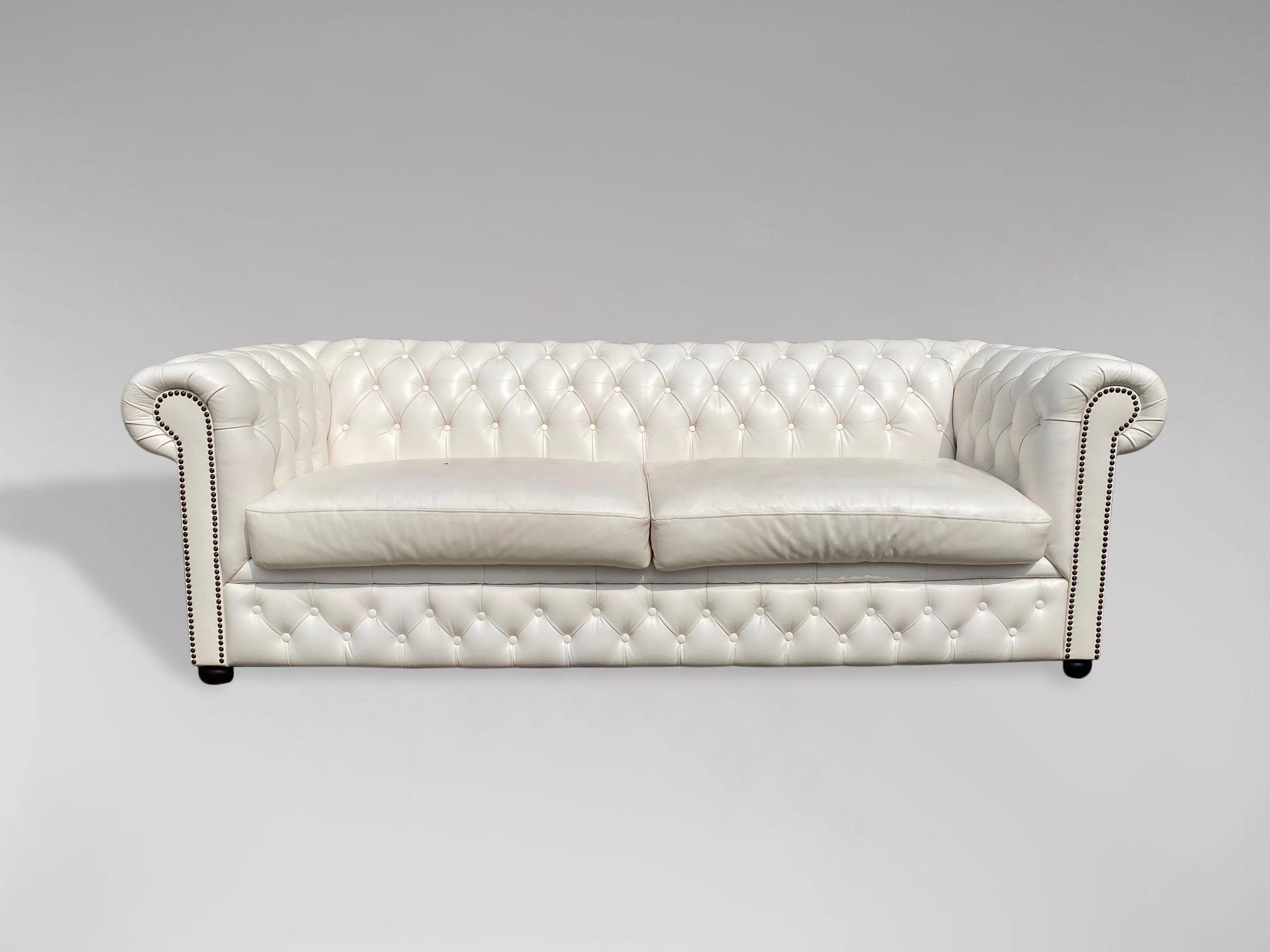 A 20th century large three seater white leather chesterfield with two large loose cushions, raised on 4 bun feet. A fine example of a good quality comfortable chesterfield. Very comfortable seating. A rather pleasing example.

The dimensions