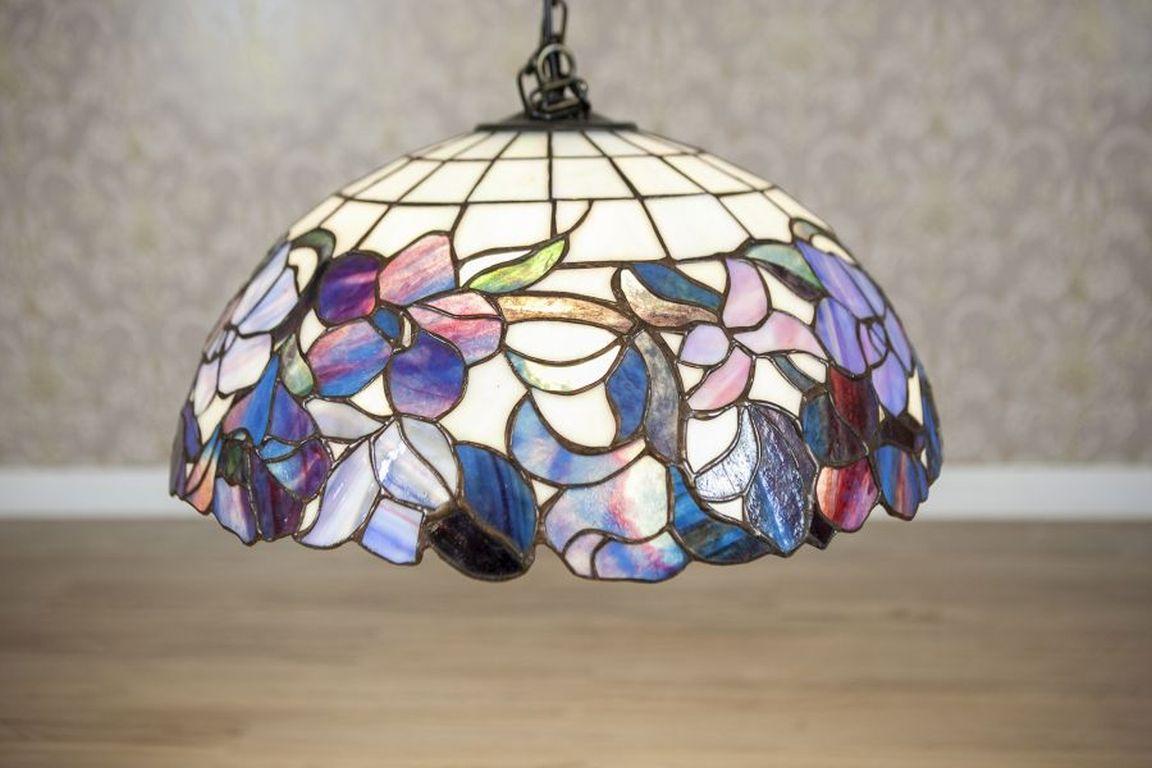 20th-Century Tiffany Hanging Lamp With Multicolored Glass Shade

The lampshade is made of multicolored glass with a floral motif, fitted for a single light bulb. The item is in particularly good condition. Cord length: 100 cm, the cord might be
