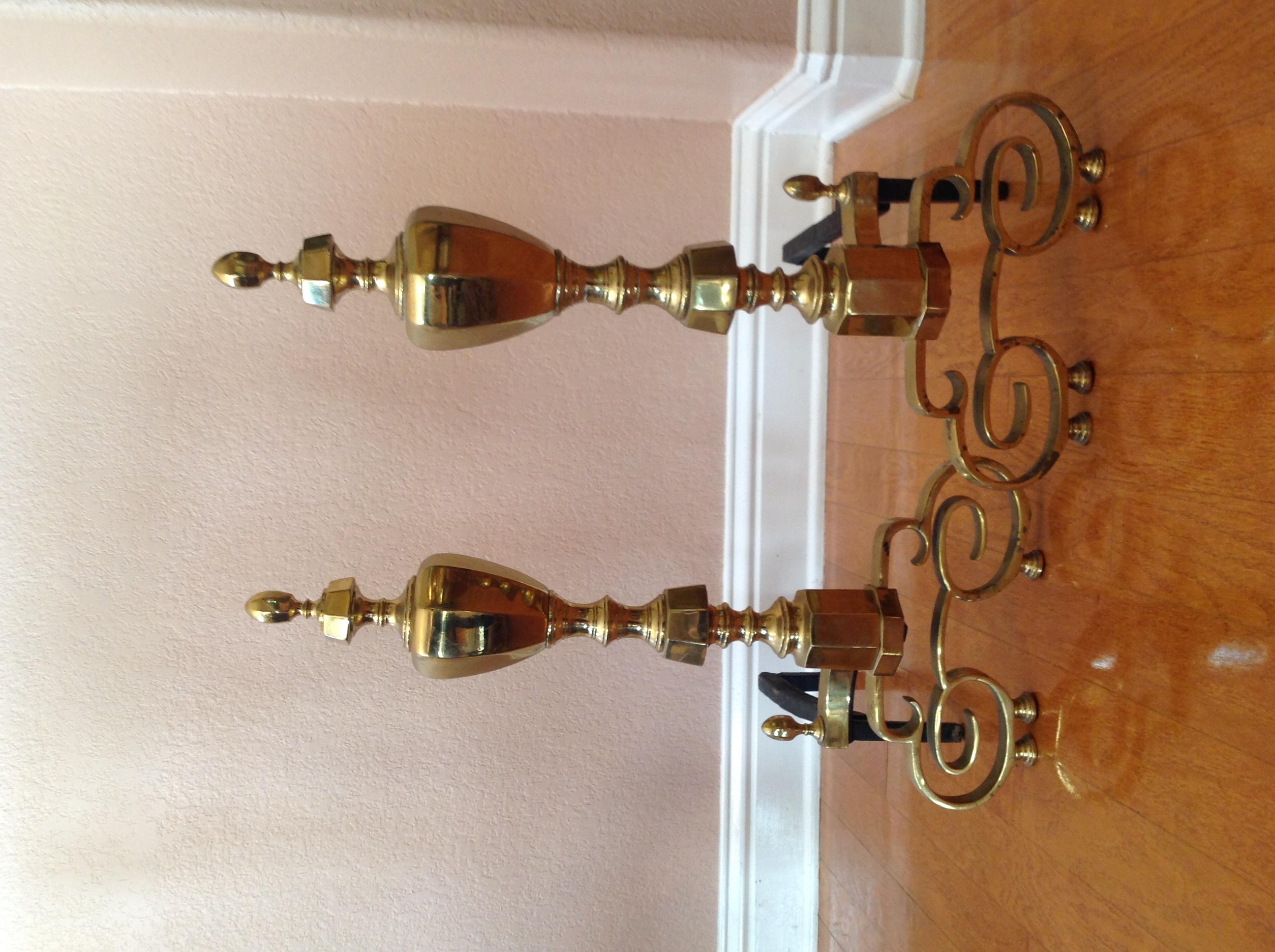 Antique solid brass and iron andirons from a stately city home. They are early 20th-century American-made andirons, and are taller than what is often found today from this era.

The brass has a lovely luster, as well as some patina and scratching.
