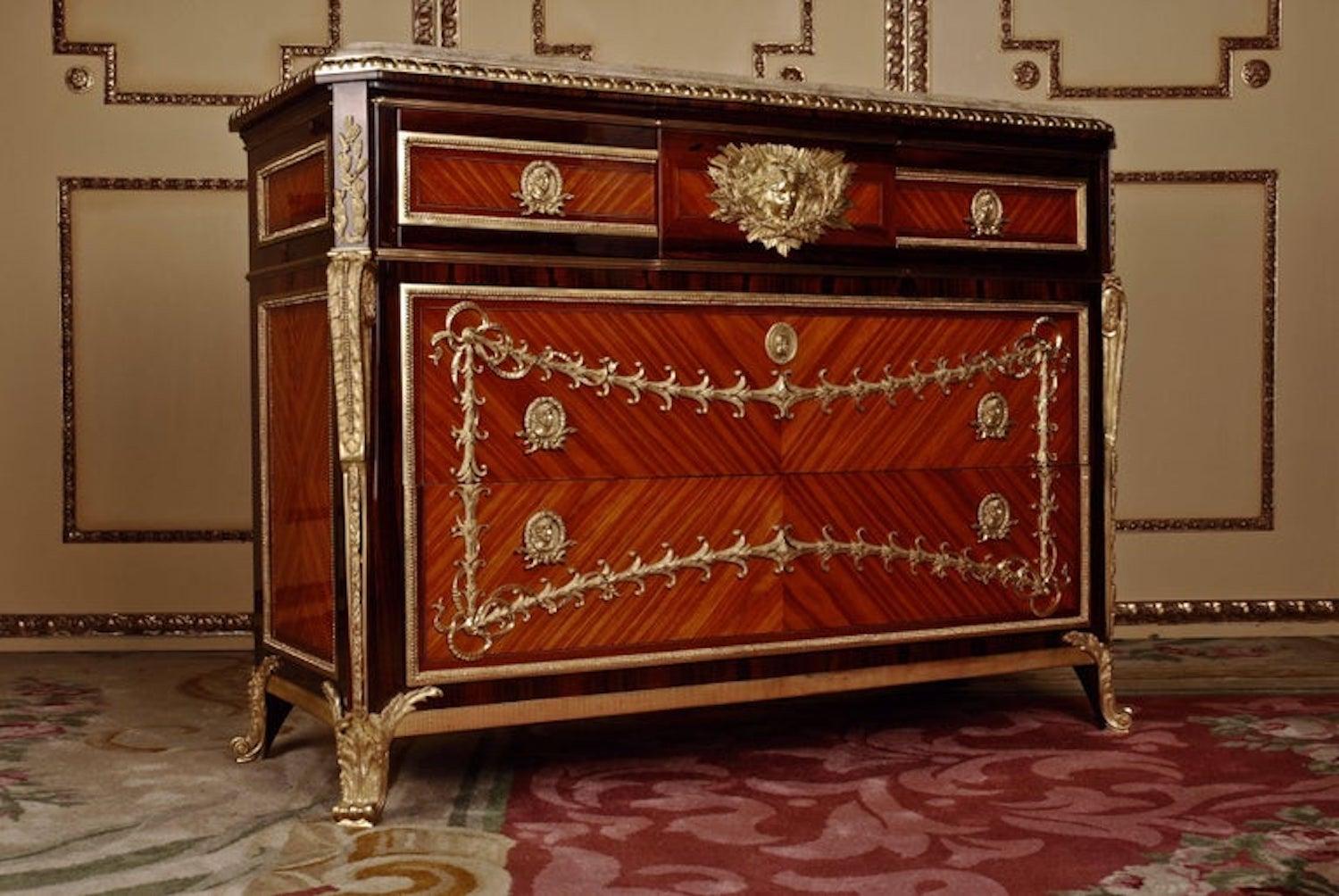 Commode after the original model from Jean Henri Riesener in transition style.
Lightly modified model after an original by Jean Henri Riesener
(1734–1806). solid pine.
Rectangular corpus on bronze caps ending feet. The middle drawer is engraved with