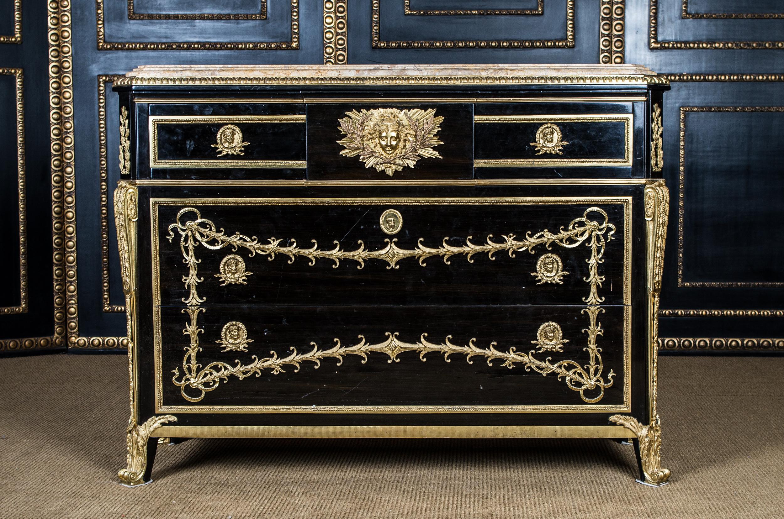 Commode after the original model from Jean Henri Riesener in transition style. Lightly modified model after an original by Jean Henri Riesener (1734-1806). Black ebonized rectangular corpus on bronze caps ending feet. The middle drawer is engraved