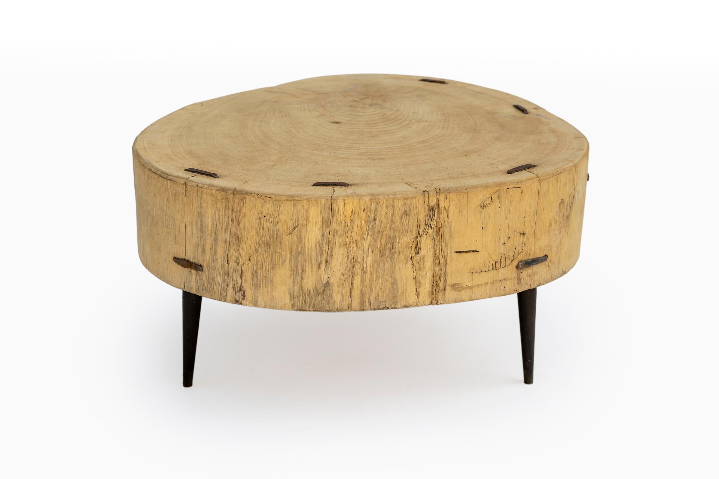 Cette étonnante table artisanale britannique du XXe siècle est formée à partir d'un tronc d'arbre naturel et repose sur des pieds en fer forgé à la main. Elle allie la chaleur organique et moderne à la force sculpturale. Le plateau en bois massif