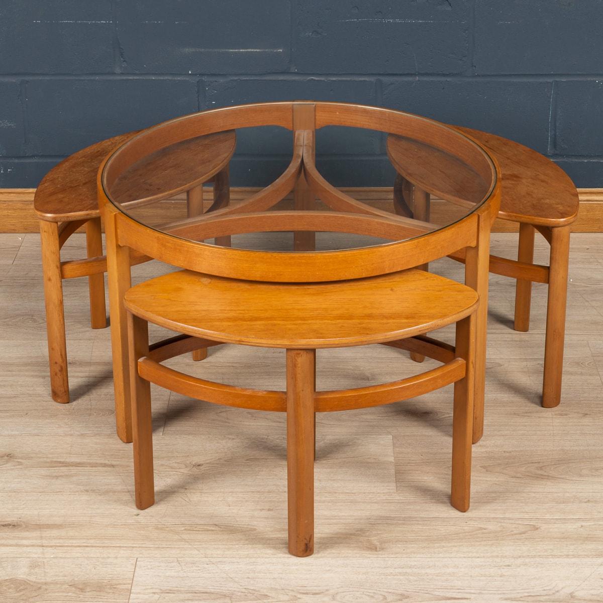 A beautiful piece of mid-century design from England. Made entirely out of teak wood, under the beautifully designed large table frame which is equipped with a glass plate, there are three leaf-shaped side tables which are stored perfectly to form a