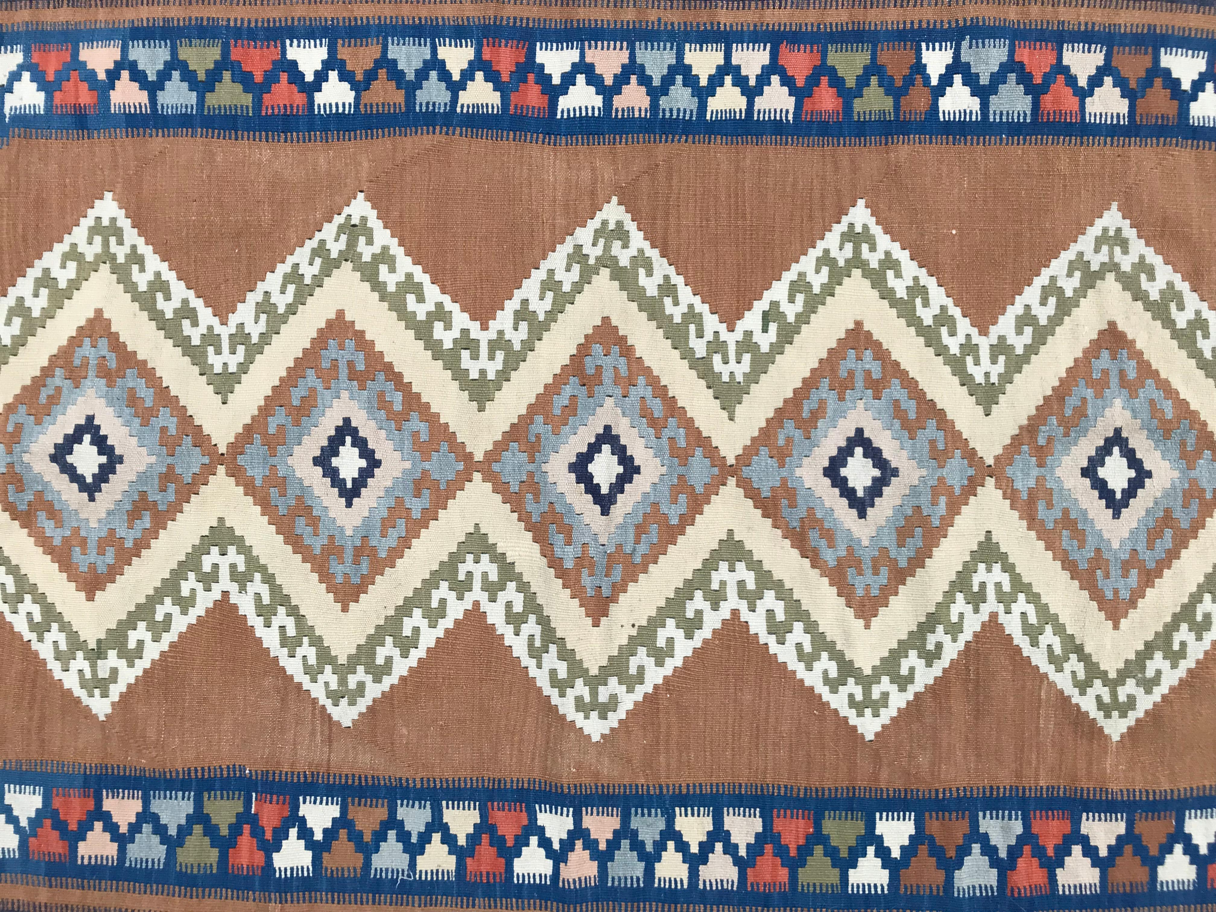 Discover the timeless elegance of this vintage Turkish flat Kilim featuring a captivating geometrical Caucasian design. Adorned with beautiful colors, including shades of yellow and light brown, this piece is meticulously handwoven with wool on a