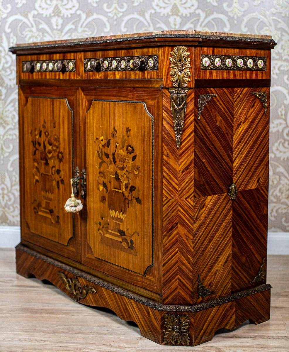 20th-Century Richly Inlaid Two-Leaf Cabinet with Marble Top

We present you this two-leaf cabinet, circa after 1945, stylized as Louis XV furniture.
The corpus with cut corners is placed on an advanced cornice and topped with a marble board.
The