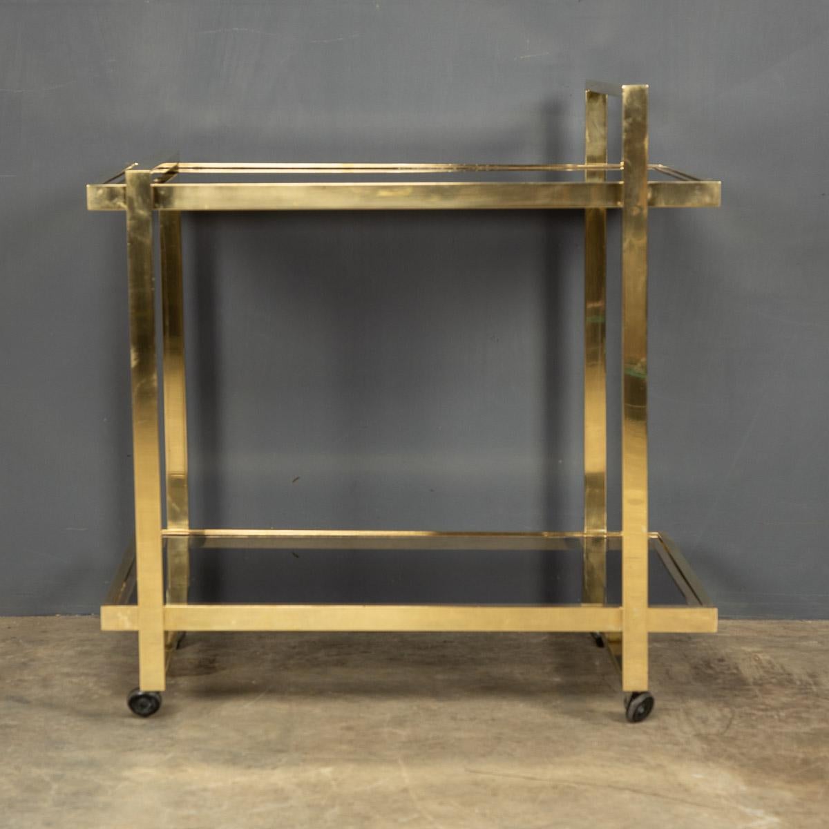 Stylish mid-20th century two-tier brass drinks trolley with lift off serving tray and bottle holder.

Condition
In good condition - some wear consistent with age.

Size
Width: 75cm
Depth: 53cm
Height: 78cm
Height top shelf: 67cm.