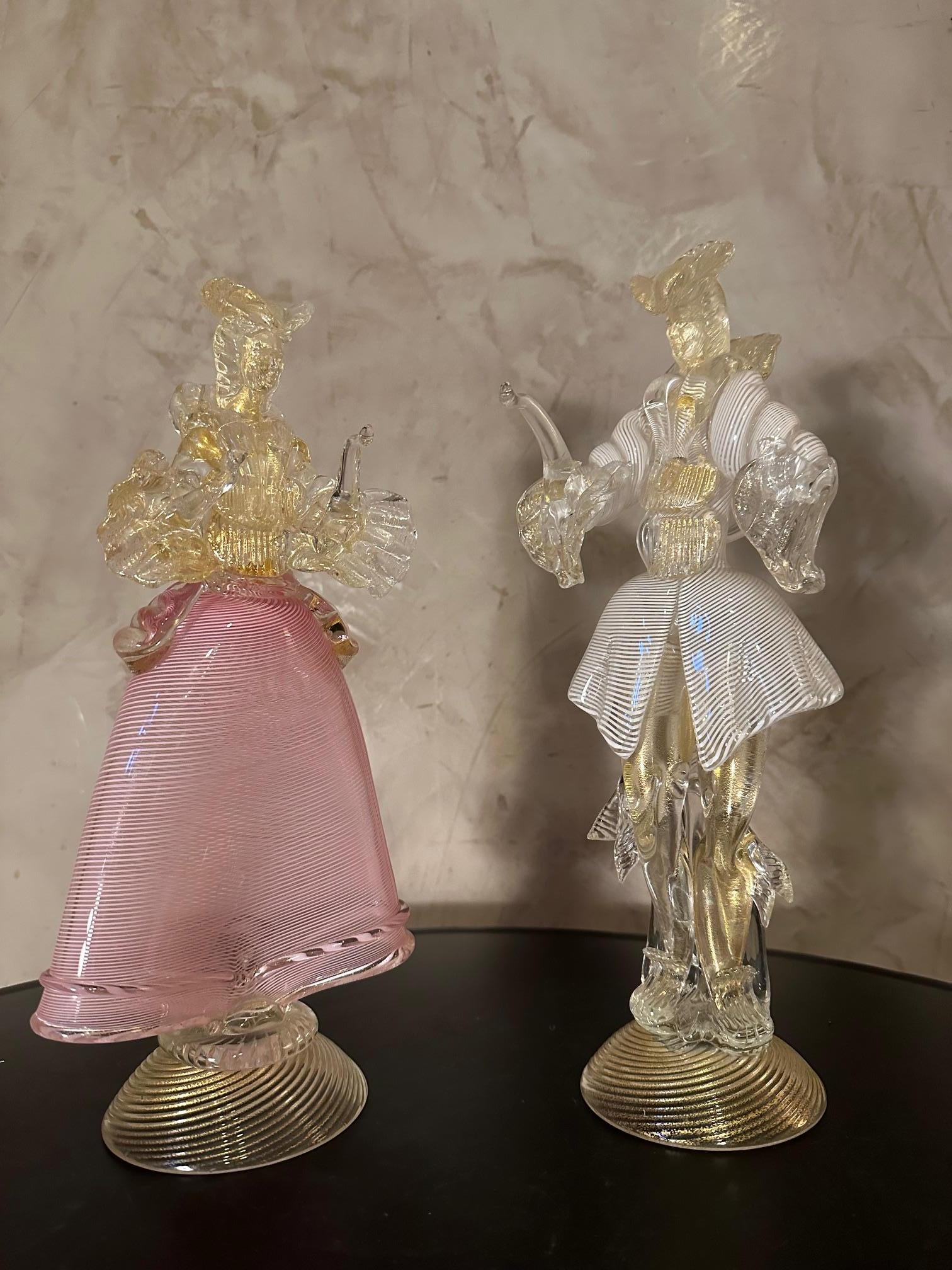 Couple of Murano Glass characters dating from the 1950s representing a Venetian couple dressed in traditional comedia dell'arte costume.
Made with a delicate blown glass technique specific to Venetian workshops. Gold and white colors for the