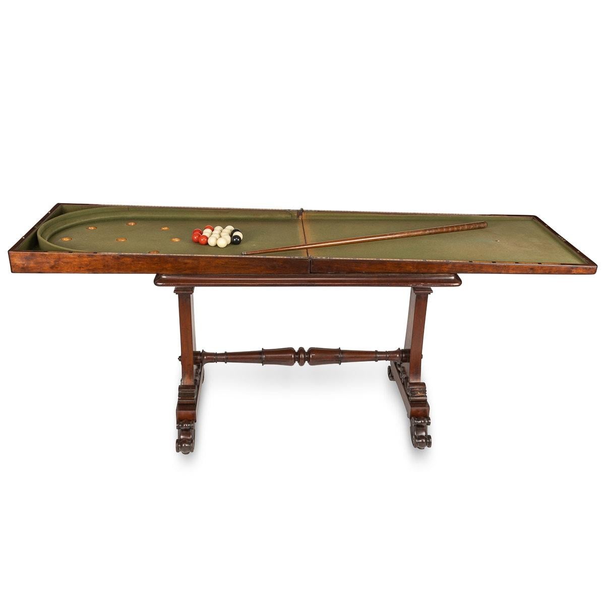 Antique early 20th Century Victorian mahogany bagatelle folding table game, with 18 original balls, cue and rule book. This table is supported by a beautifully carved wooden base, with a turned wooden support beams. The tabletop folds in half