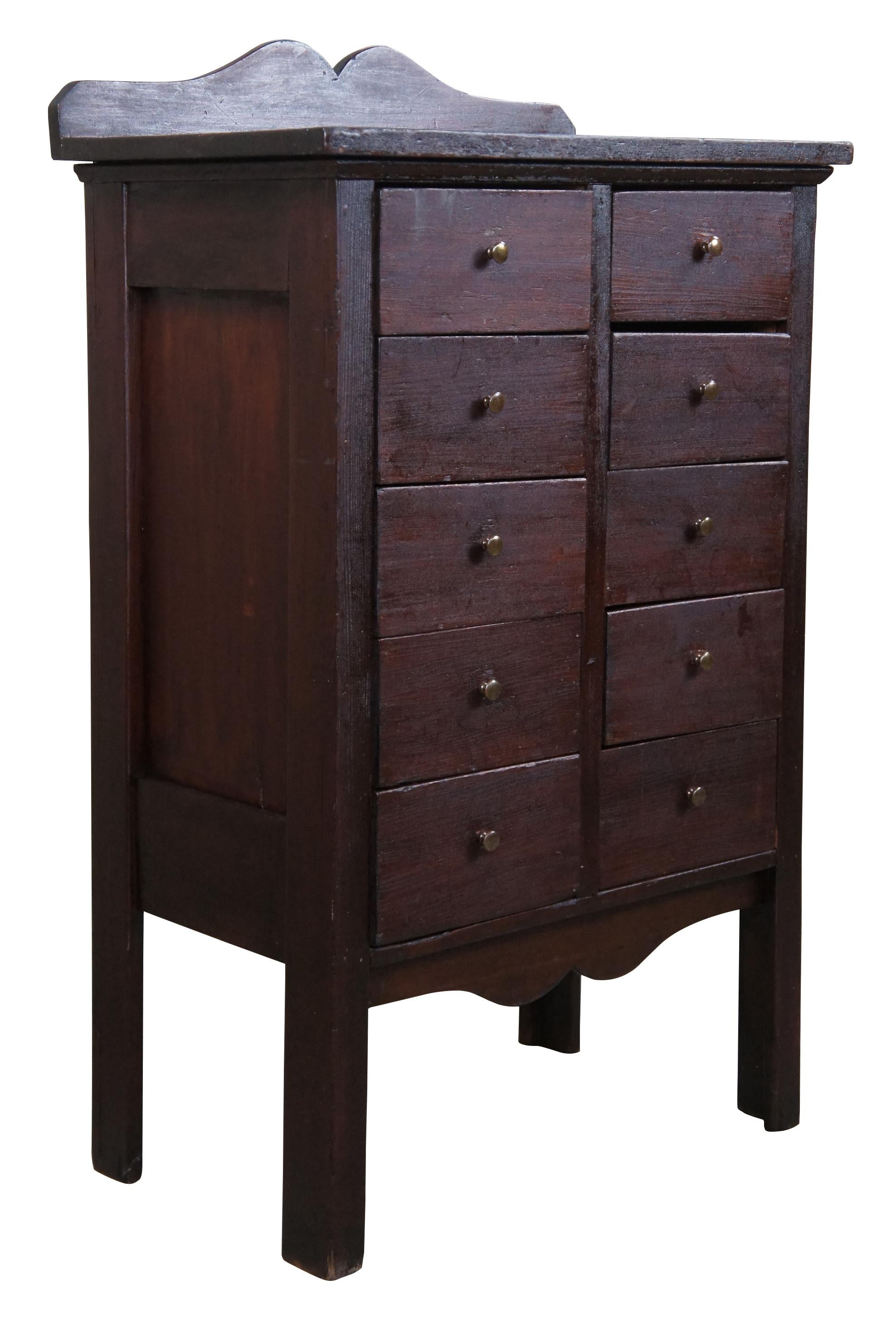 Vintage Apothecary cabinet or chest, circa 1940s. Made from pine with a mahogany color stain. Features a rectangular form with serpentine cut aprons and ten drawers with brass knobs. 

Measures: 18.5