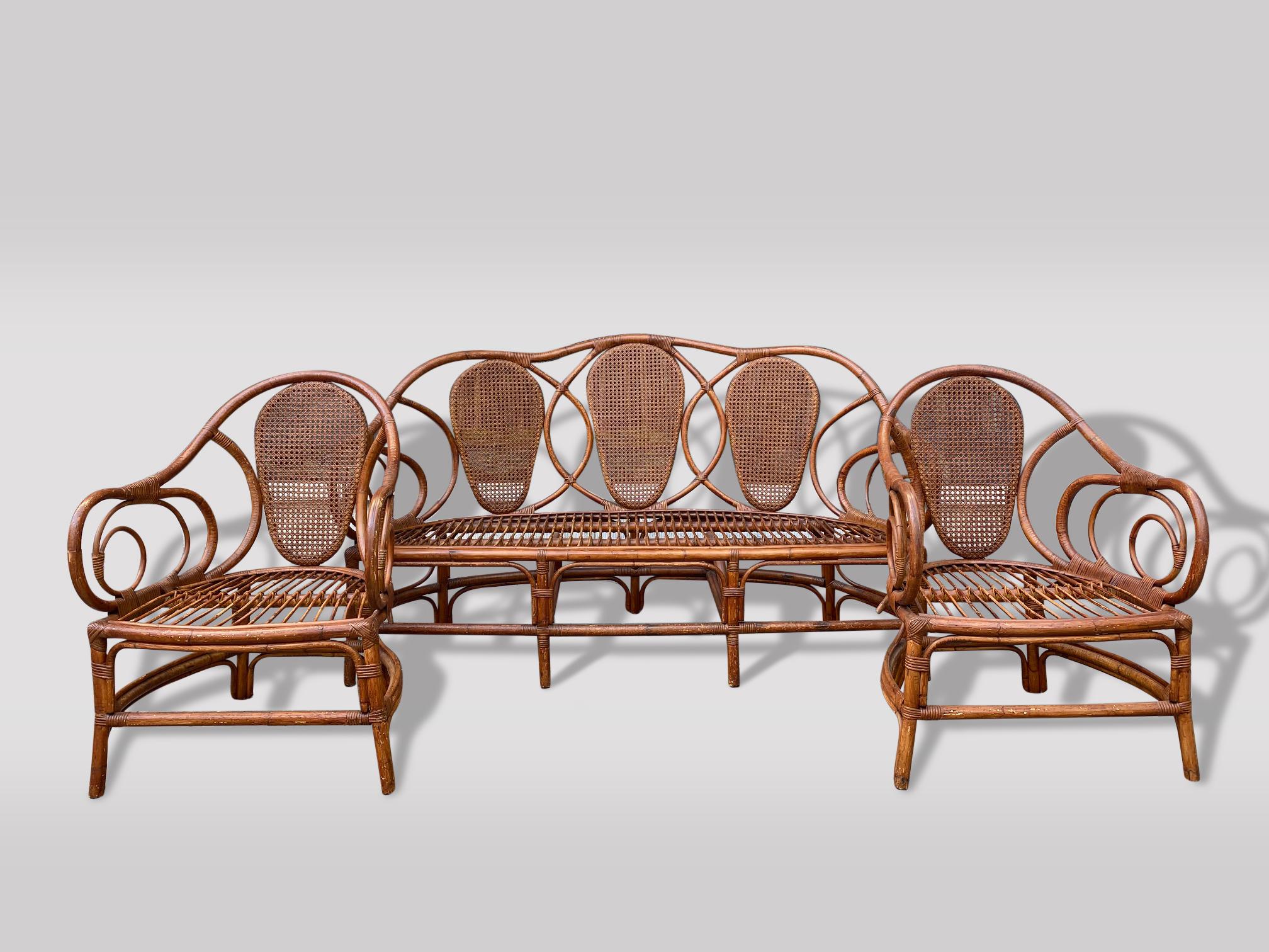 A rare and spectacular mid 20th century 3 piece bentwood garden lounge furniture set of charm features bamboo & rattan structure with cane circular shaped backs. Comprising a three seater settee with circular shaped back, scrolling arms upon