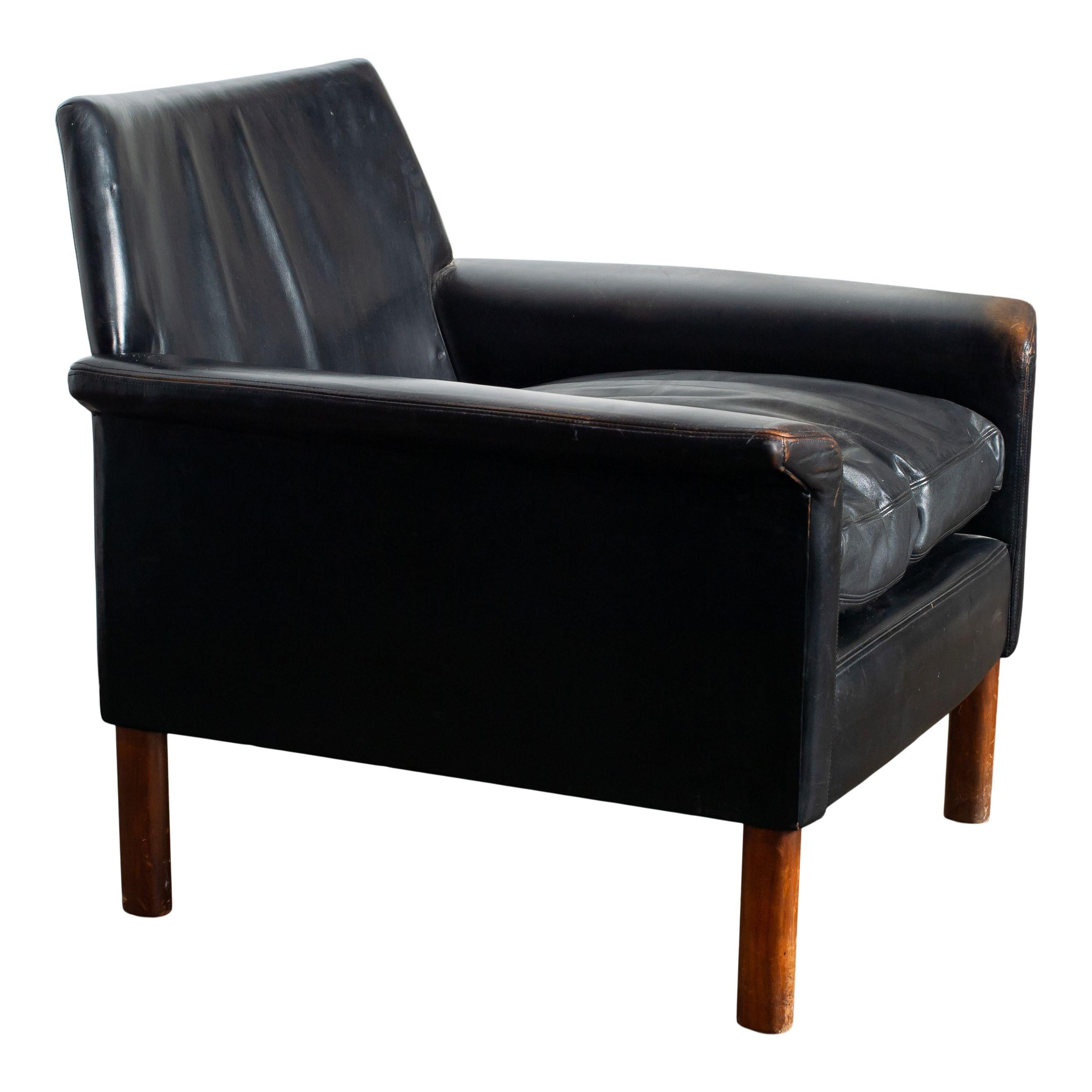 Fauteuil vintage en cuir noir avec pieds en bois. Un fauteuil vintage classique et intemporel qui s'adapte parfaitement à tous les espaces. Apportez une ambiance vintage et moderne du milieu du siècle à votre intérieur avec cette chaise en cuir. 
