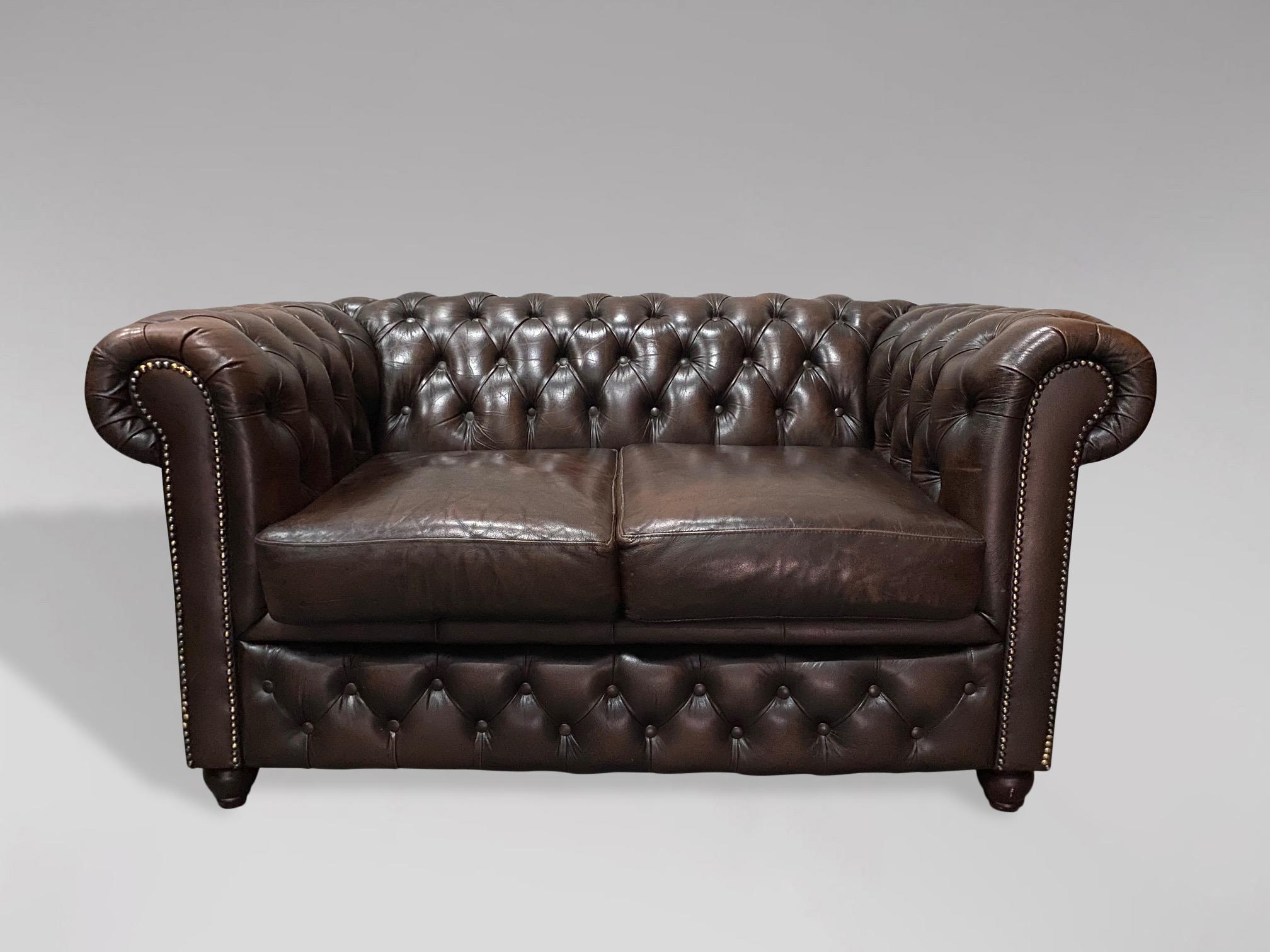 A 20th century large two seater vintage brown leather chesterfield with two large loose cushions, raised on 4 bun feet. A fine example of a good quality comfortable chesterfield. Very comfortable seating. A rather pleasing example.

The dimensions
