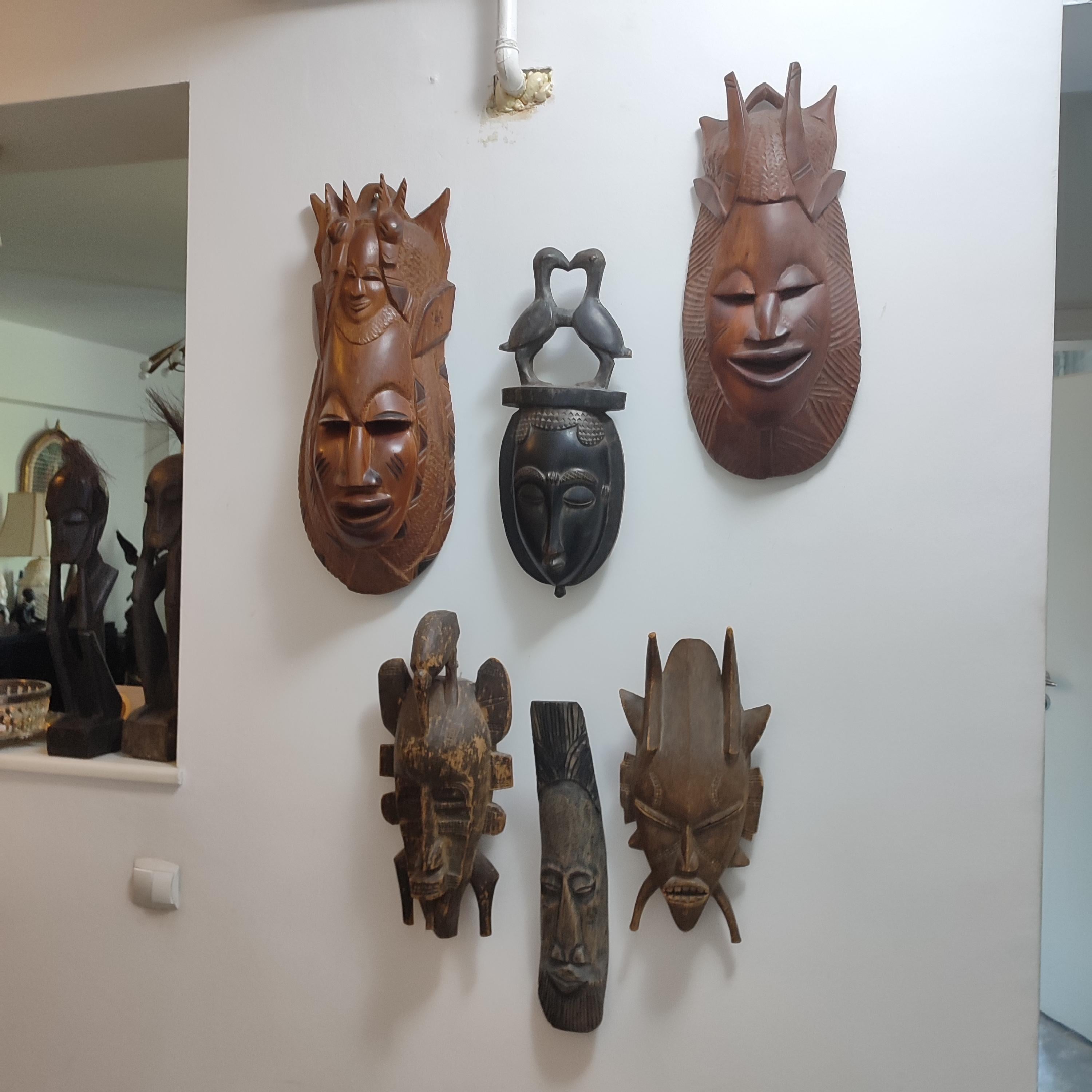 A hand carved wood wall mask, vintage from the 20th Century. African Folk Art. 
Handmade and carved from a single piece of exotic wood, in a manner specific to traditional African art. Hand carved African mask with decorative geometric ornaments,