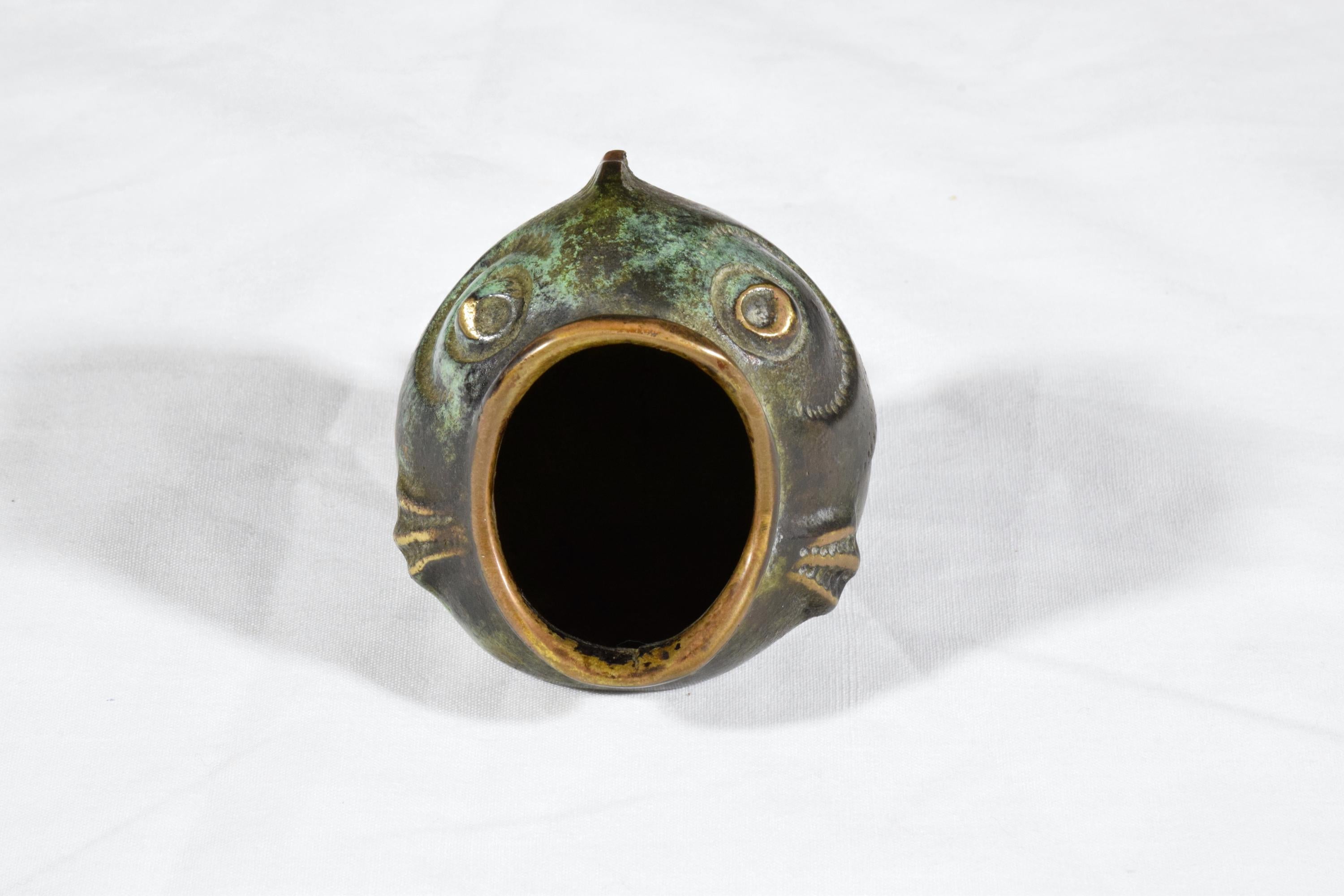 A 20th century vintage collectible ashtray by Walter Bosse crafted out of brass with its distinctive green tint and dotted eyes in Austria, circa 1950s.
 