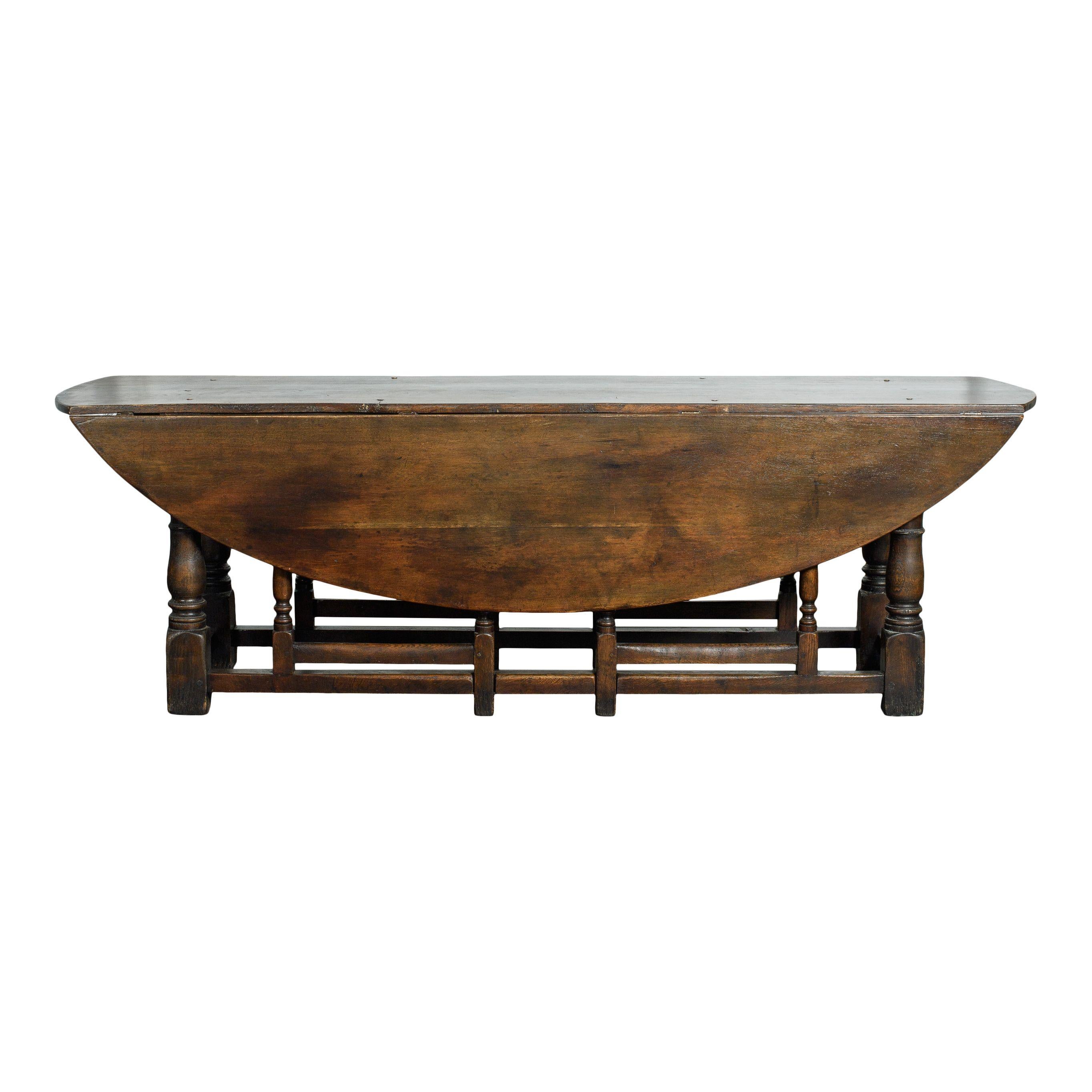 Table à pieds ovale en bois vintage avec feuilles pour augmenter/diminuer la taille, importée de France. Avec son bois sombre scellé et ses pieds de porte en fuseau, cette pièce est d'une beauté vintage intemporelle. L'ajout parfait à tout espace de