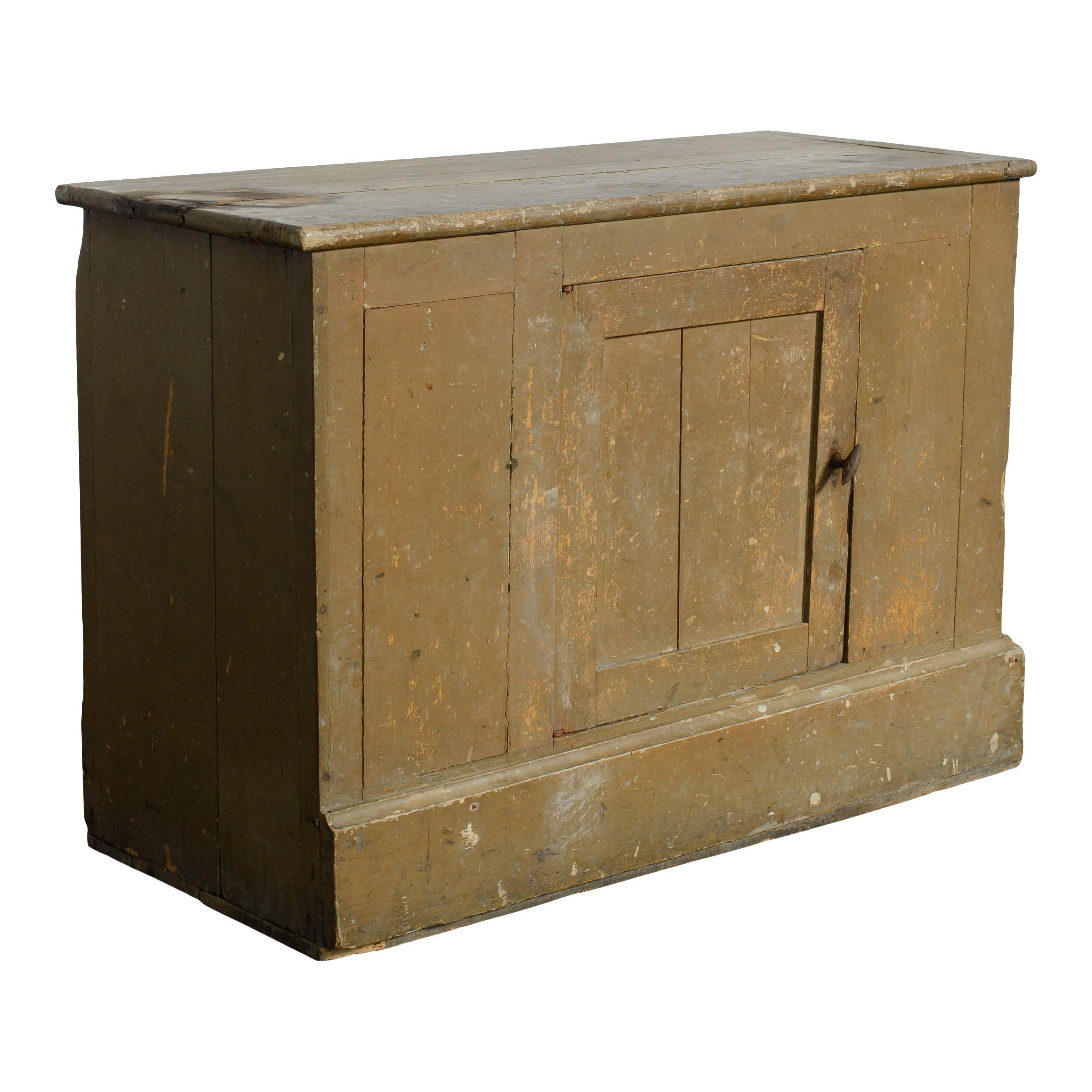 A perfect little vintage wood cabinet. The cabinet has a simple design with one small door opening to shelves in the middle, making it both a charming and functional vintage piece. The chipped olive or sage green paint also gives this piece the