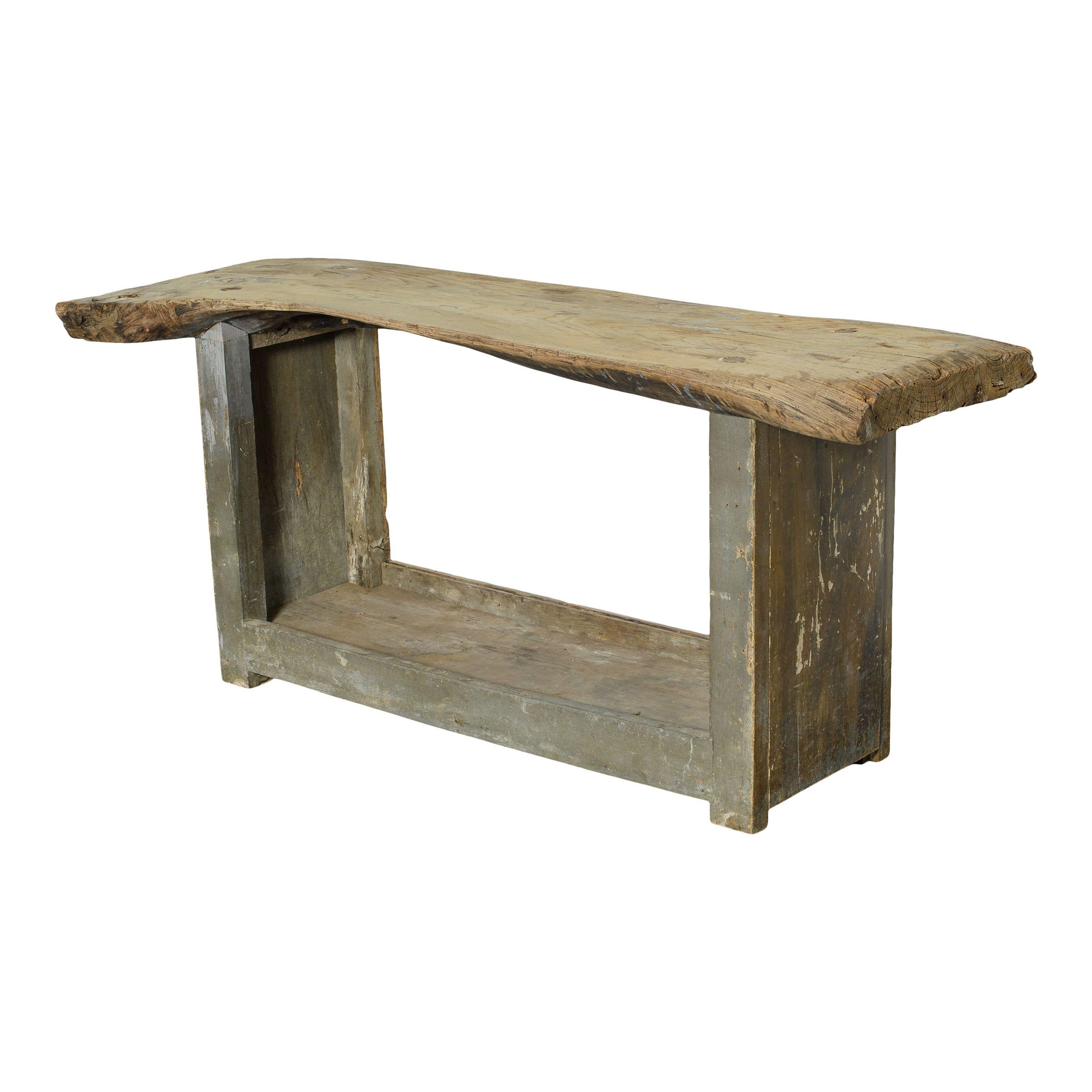 A vintage wood console table with painted grey legs from France. The natural wood table top is a beautiful and warm vintage touch. The legs are a lovely grey and feature lovely patina from years of use. The legs connect at the bottom, creating a