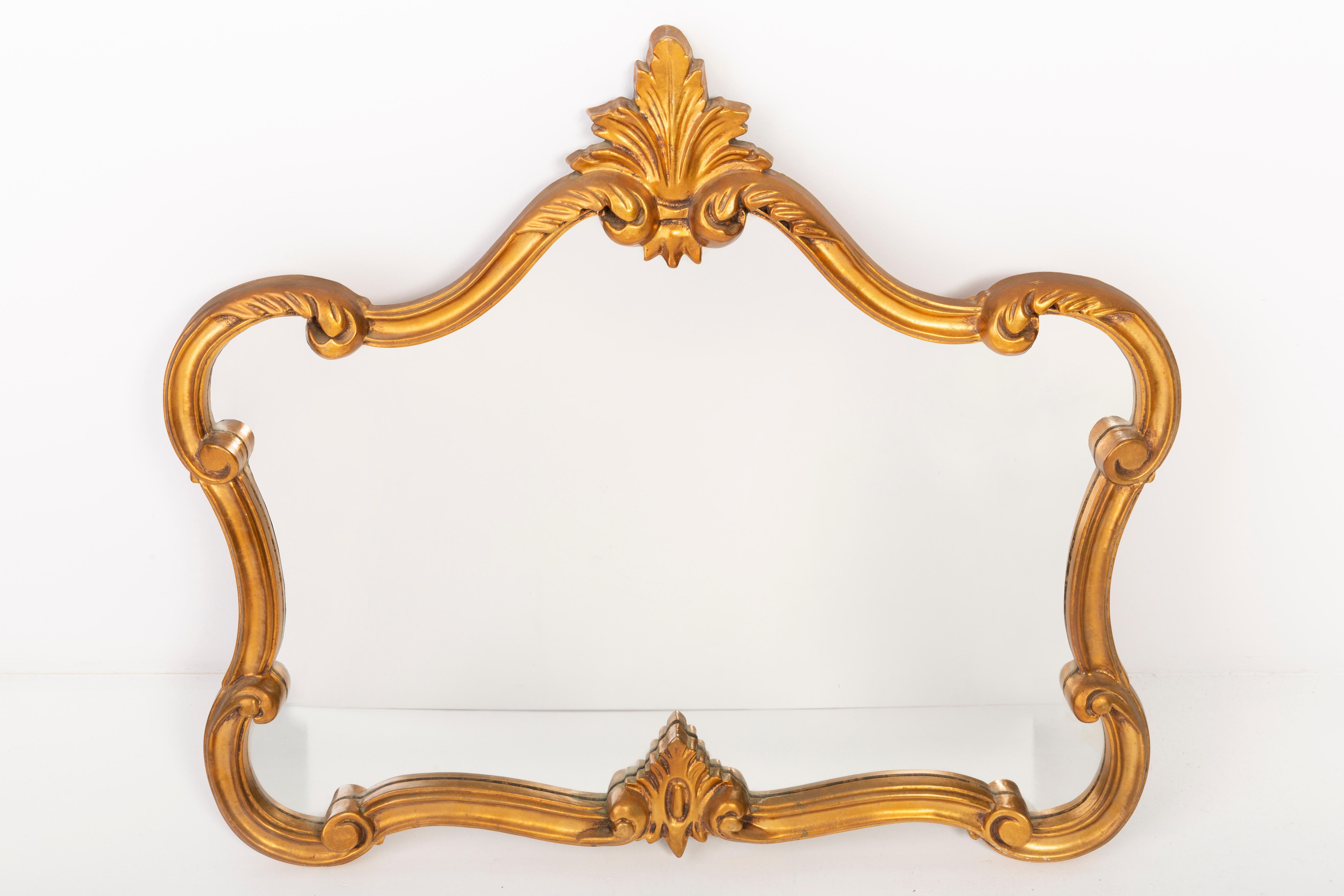 Un miroir dans un cadre décoratif doré avec des fleurs. Le cadre est en bois. Parfait pour la chambre à coucher comme décoration au-dessus du lit. Le miroir est en très bon état vintage, aucun dommage ou fissure dans le cadre. Verre original. Une