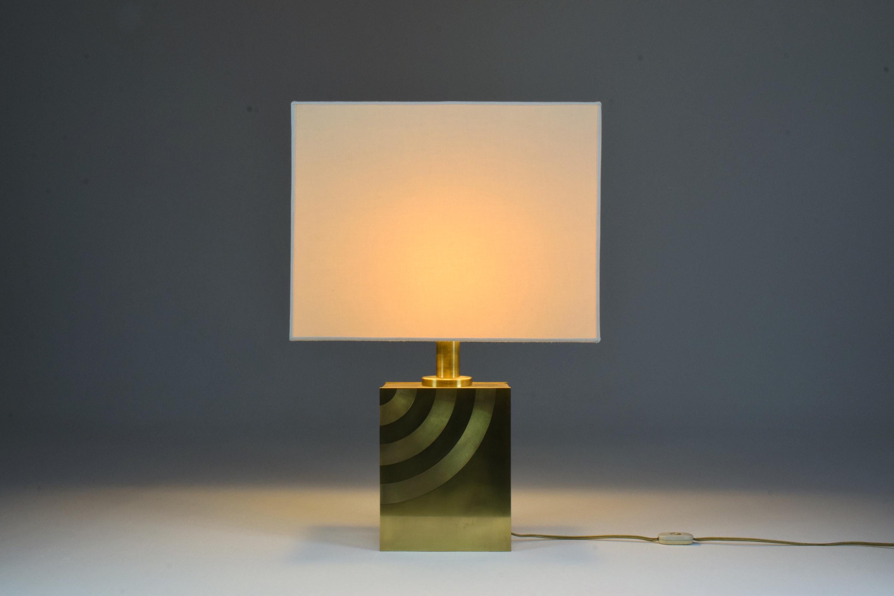 A majestic Italian vintage rectangular table lamp from the 1970s in solid gold polished brass with beautiful graphic engravings. Restored with a new fabric lampshade in the same style as the original used one, paying homage to its timeless design.