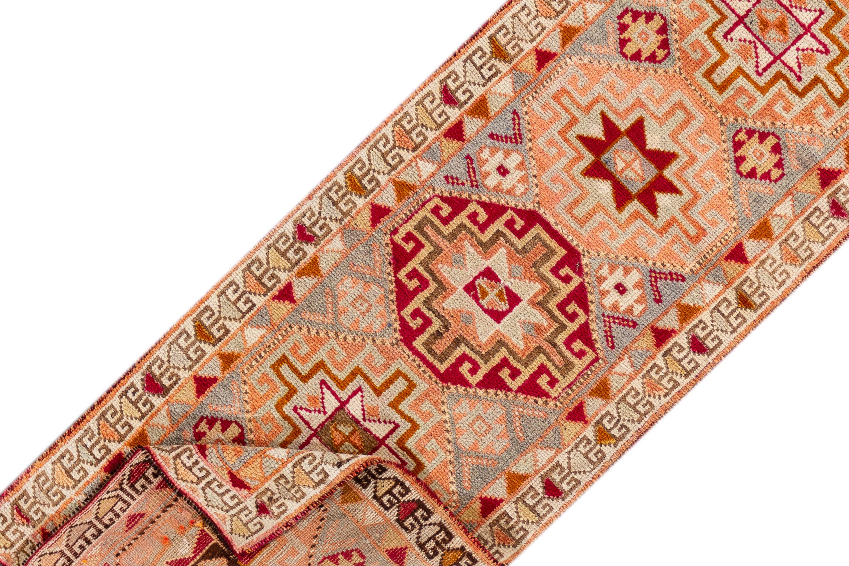 A 20th century vintage Turkish Anatolian runner rug with an all-over geometric orange motif. This rug measures at 3'1