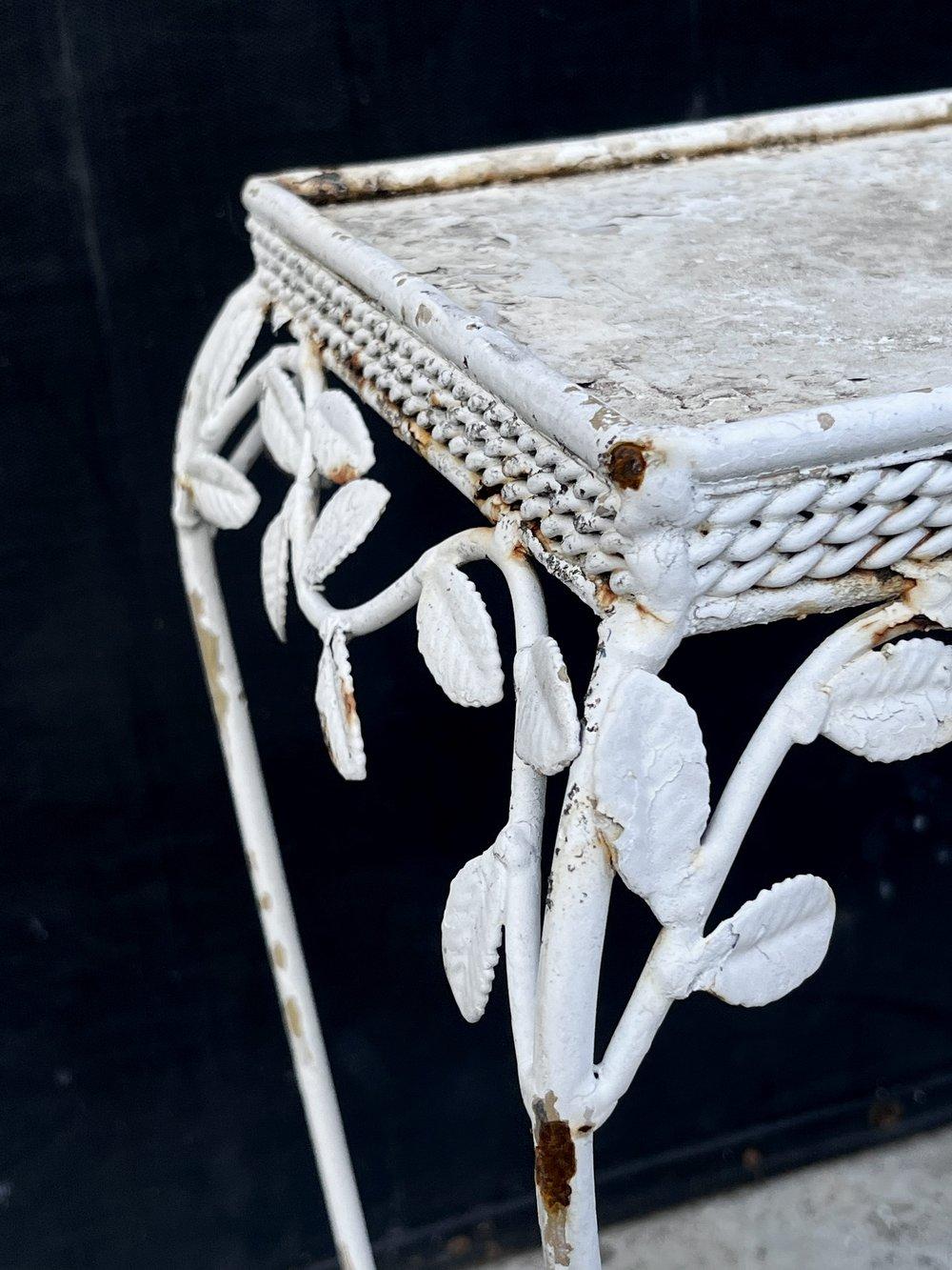 The 20th-century vintage wrought iron plant stand is inspired by the iconic Salterini style. This exquisite piece captures the essence of Salterini's renowned wrought iron designs, boasting intricate floral detailing and timeless elegance, it
